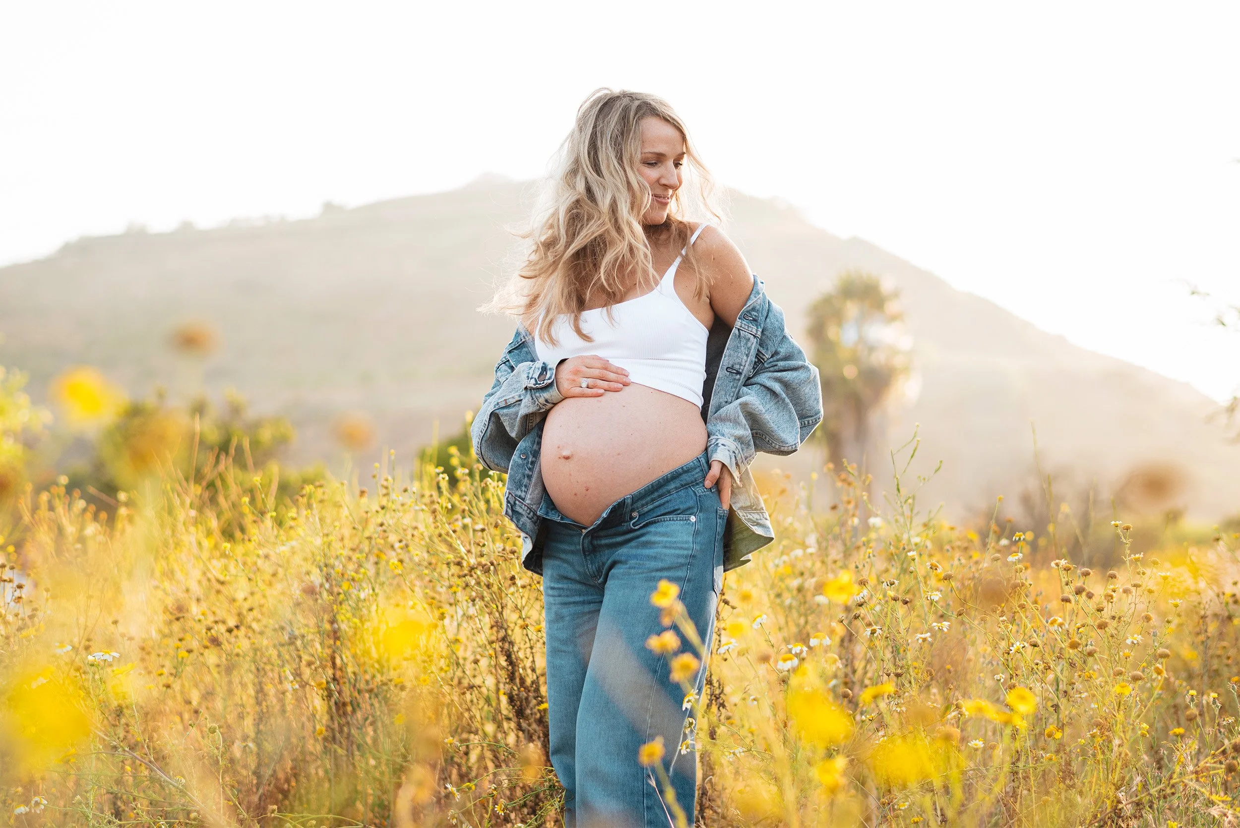 Award-winning maternity photographer in Orange County photographs mom-to-be in golden wildflower field