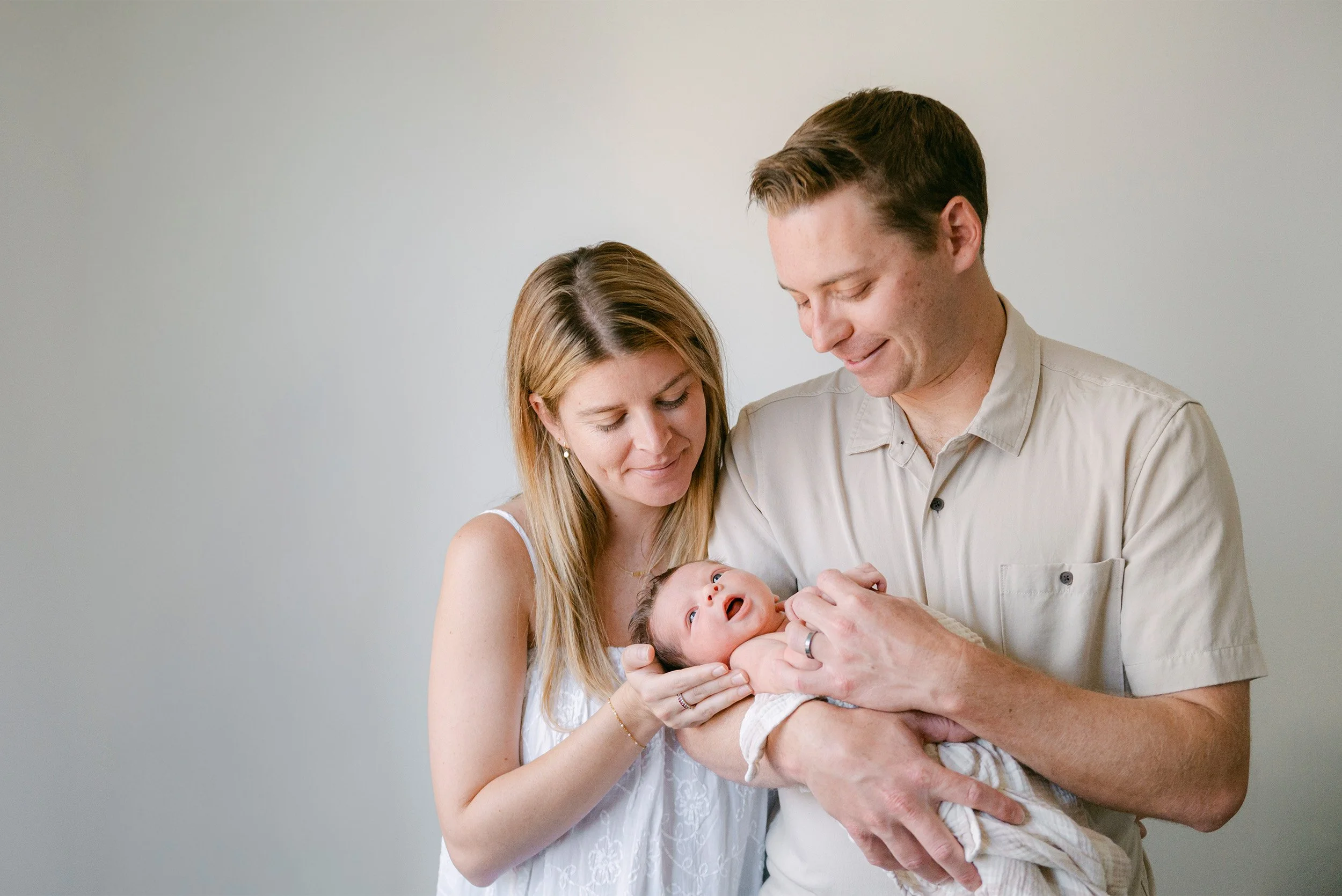 Orange County baby photographer photographs proud parents admiring their newborn during in-home session