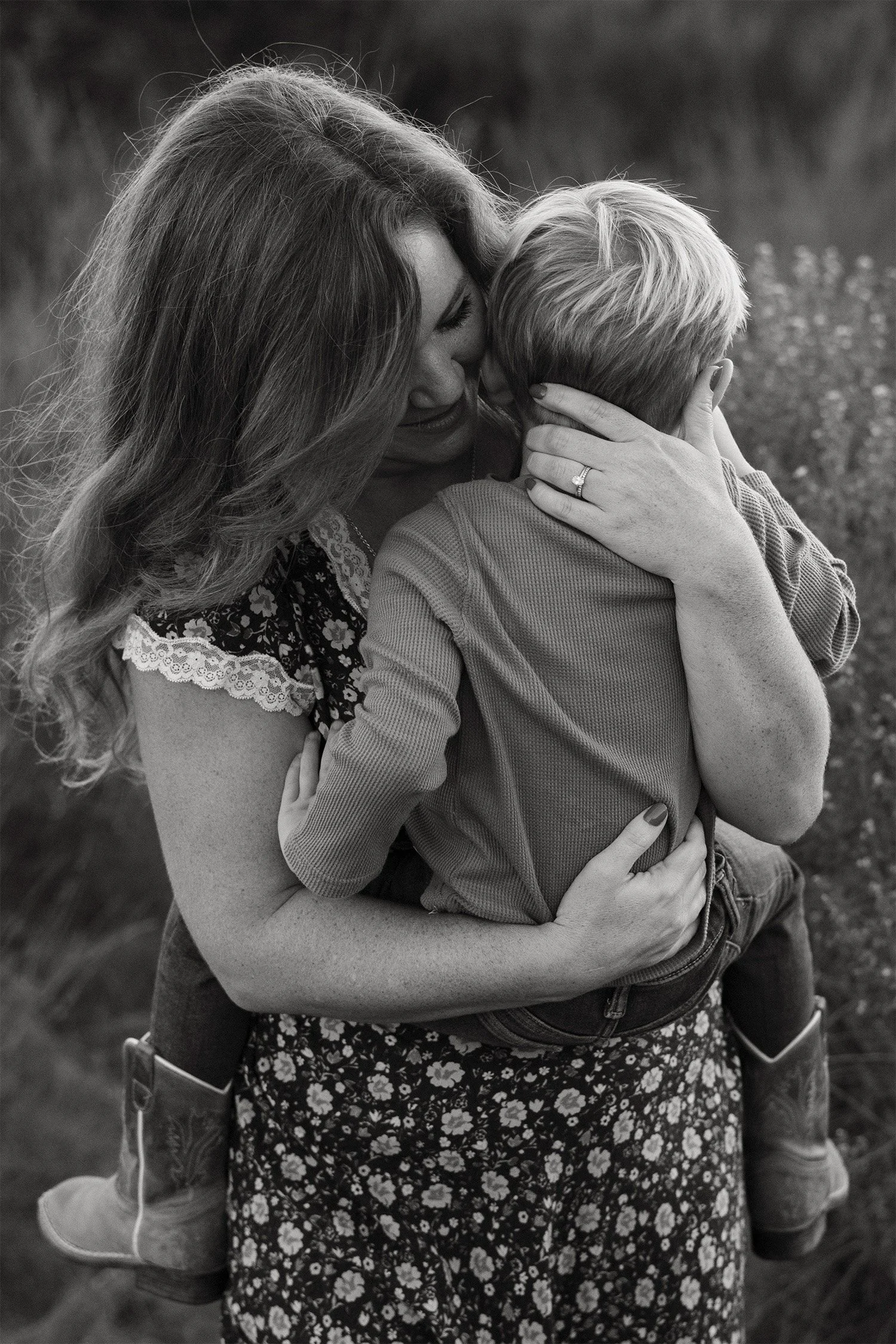 Award-winning family photographer captures a black and white photo of a tender embrace between mother and young son in an Orange County field