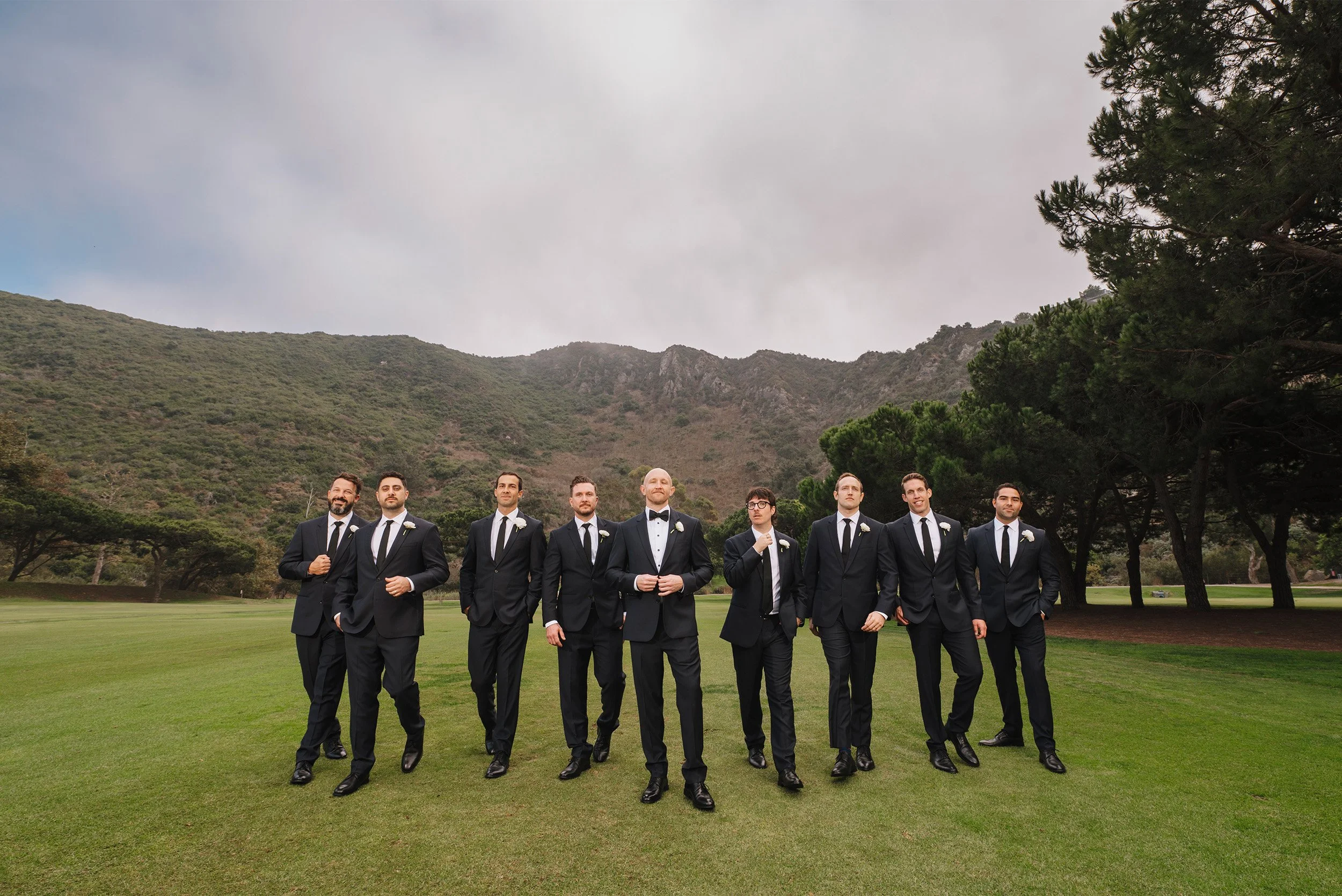 Highly recommended wedding photographer in Orange County captures groom and groomsmen walking confidently across hillside golf course lawn at The Ranch at Laguna Beach
