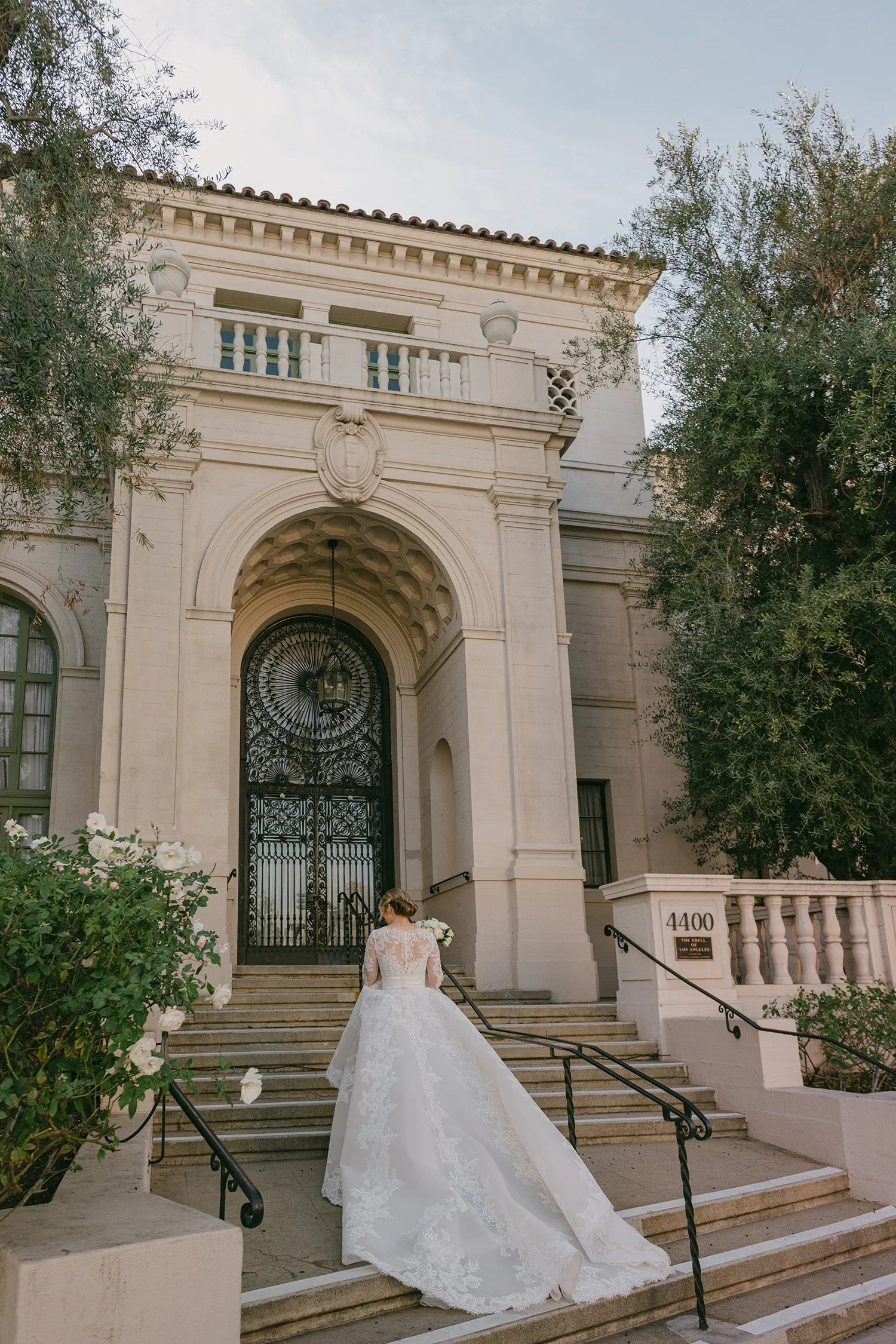 Award-winning wedding photographer in Los Angeles captures bride ascending grand staircase of the historic Ebell mansion venue