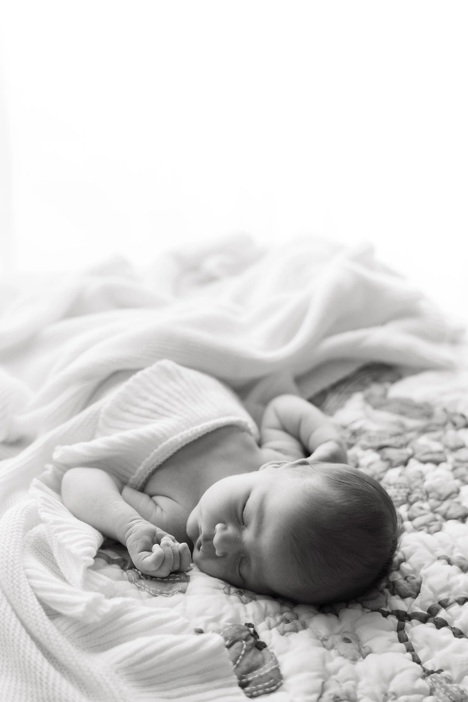 Black and white photo of sleeping newborn on floral quilt, Orange County baby photographer
