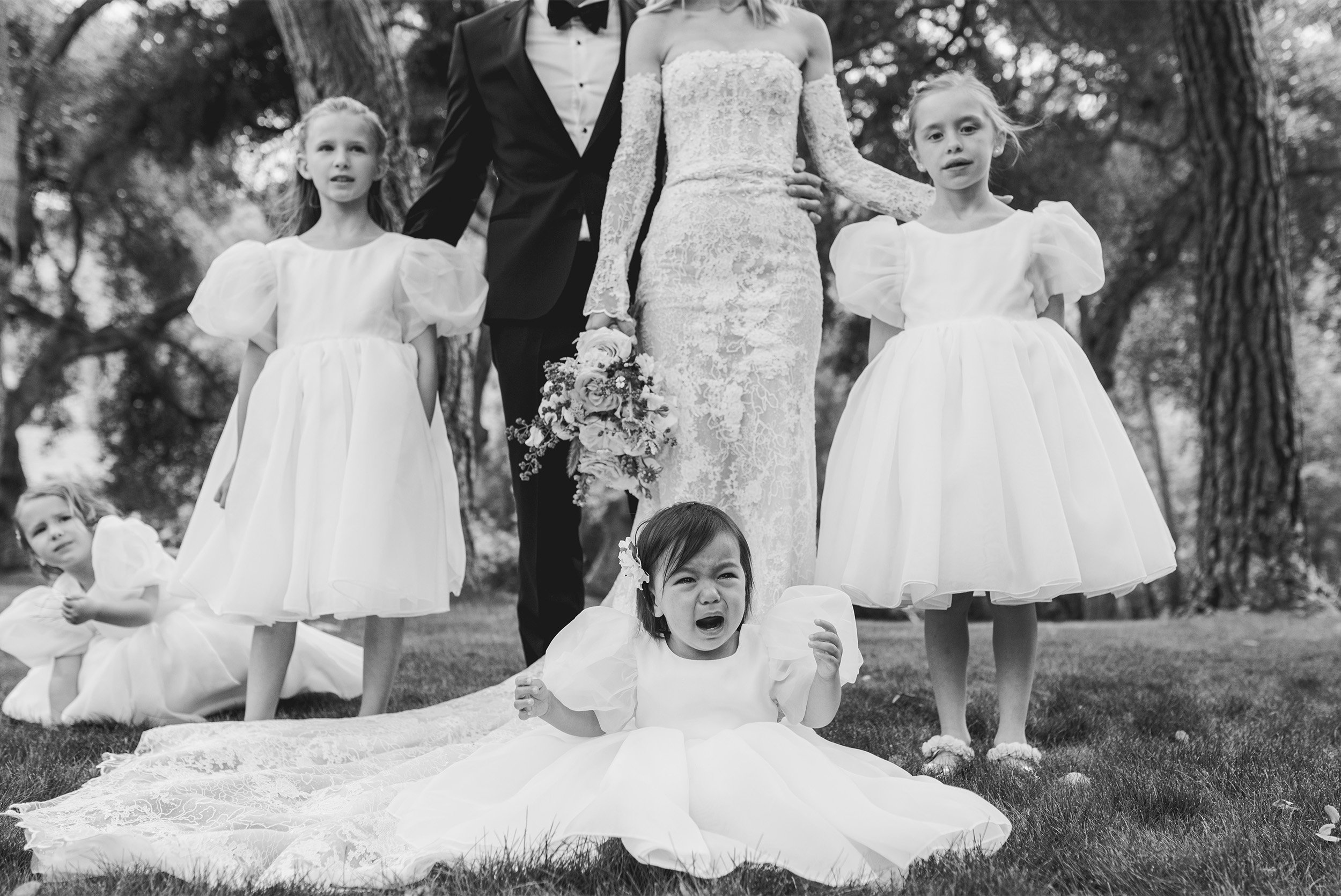 Award-winning wedding photographer in Orange County captures candid moment with crying flower girl among wedding party at Gardener Ranch in Carmel Valley, black and white