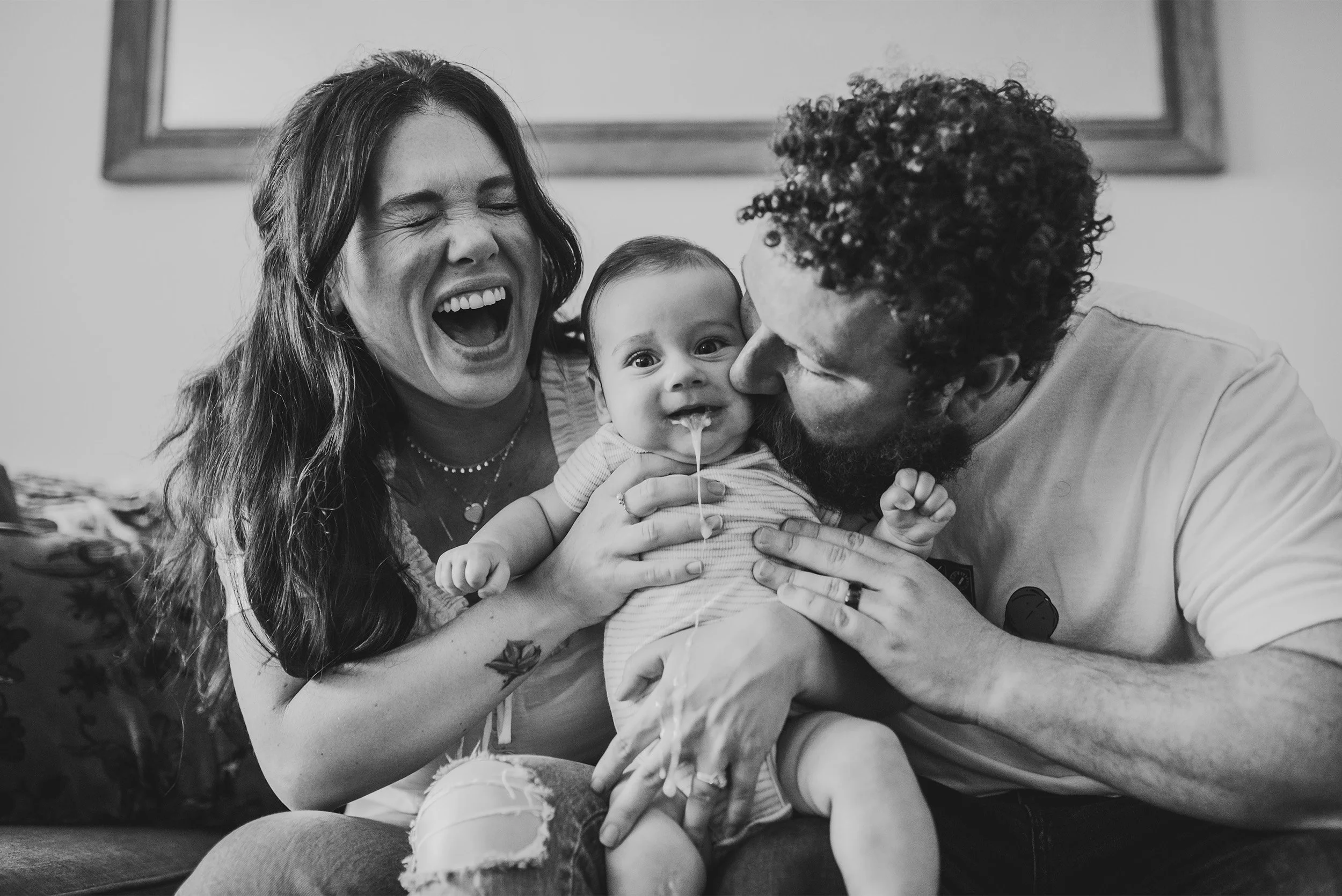 Orange County baby photographer captures candid black and white moment of parents laughing with giggling infant