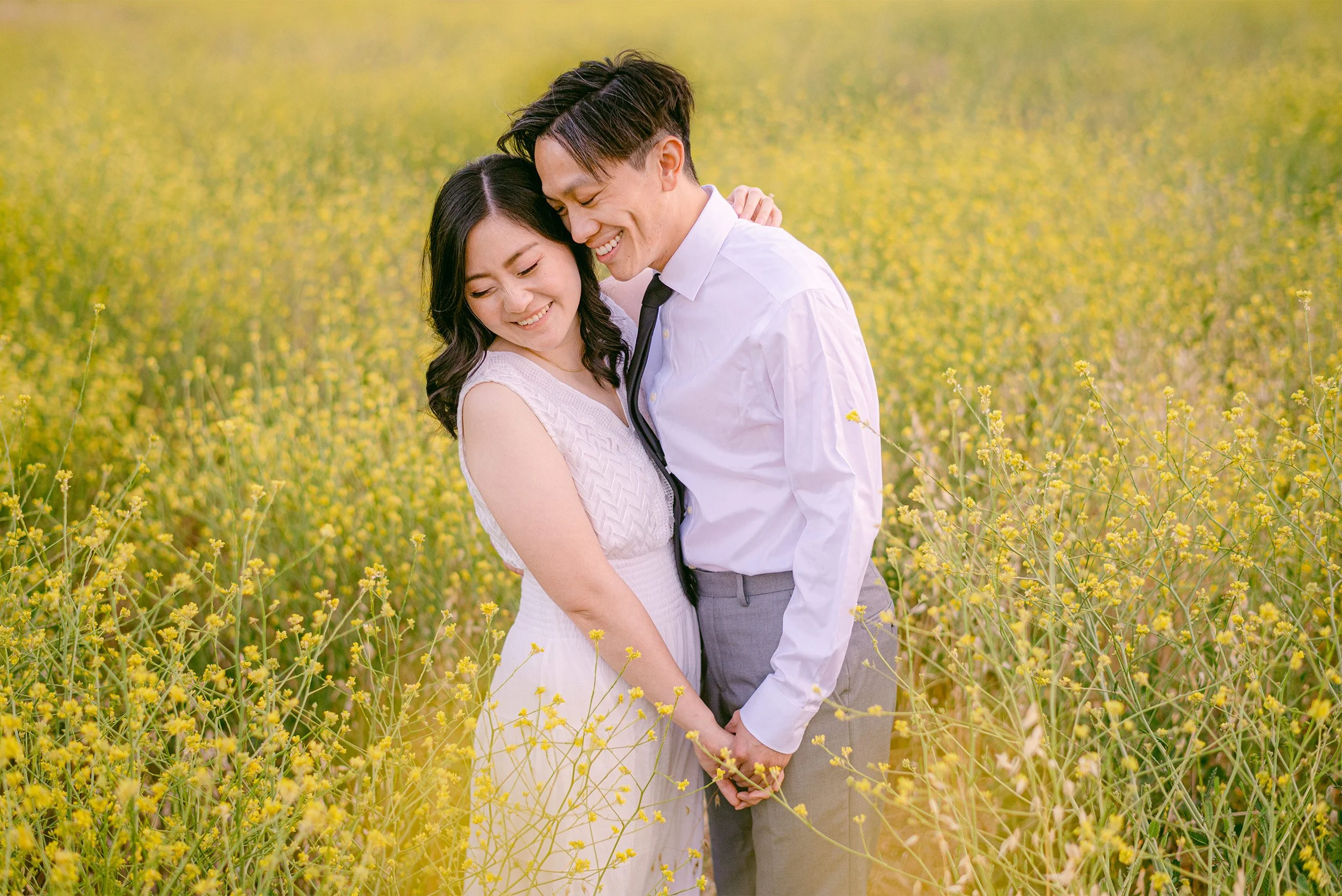 Couple embracing in golden wildflower field, award-winning engagement photographer Orange County