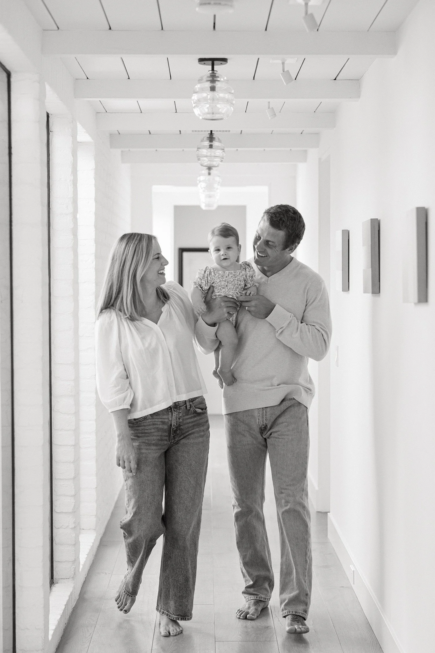 Orange County family photographer photographs parents walking down a bright hallway holding their baby daughter