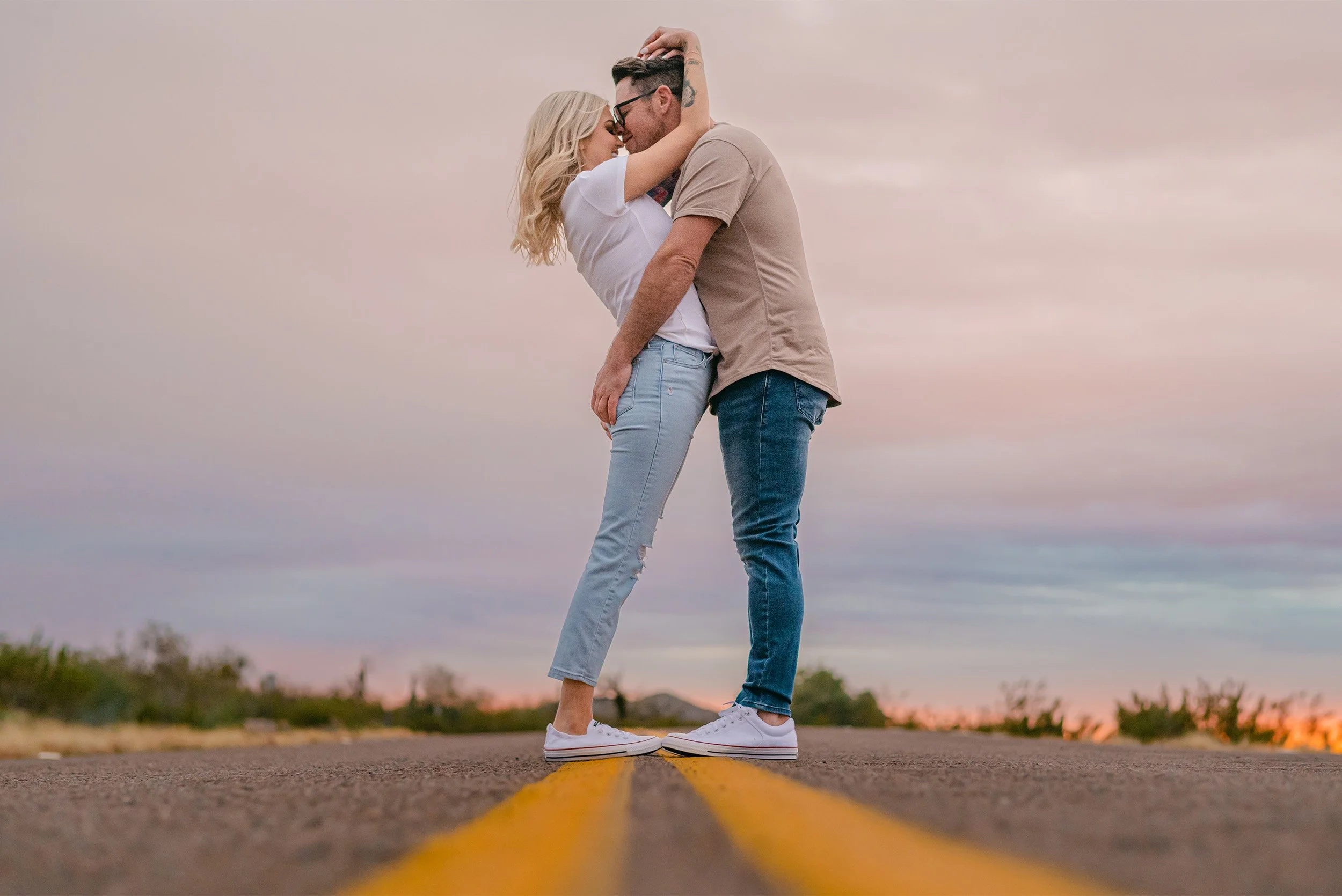 Award-winning engagement photographer in Arizona captures couple embracing on an empty road at sunset, destination engagement photographer