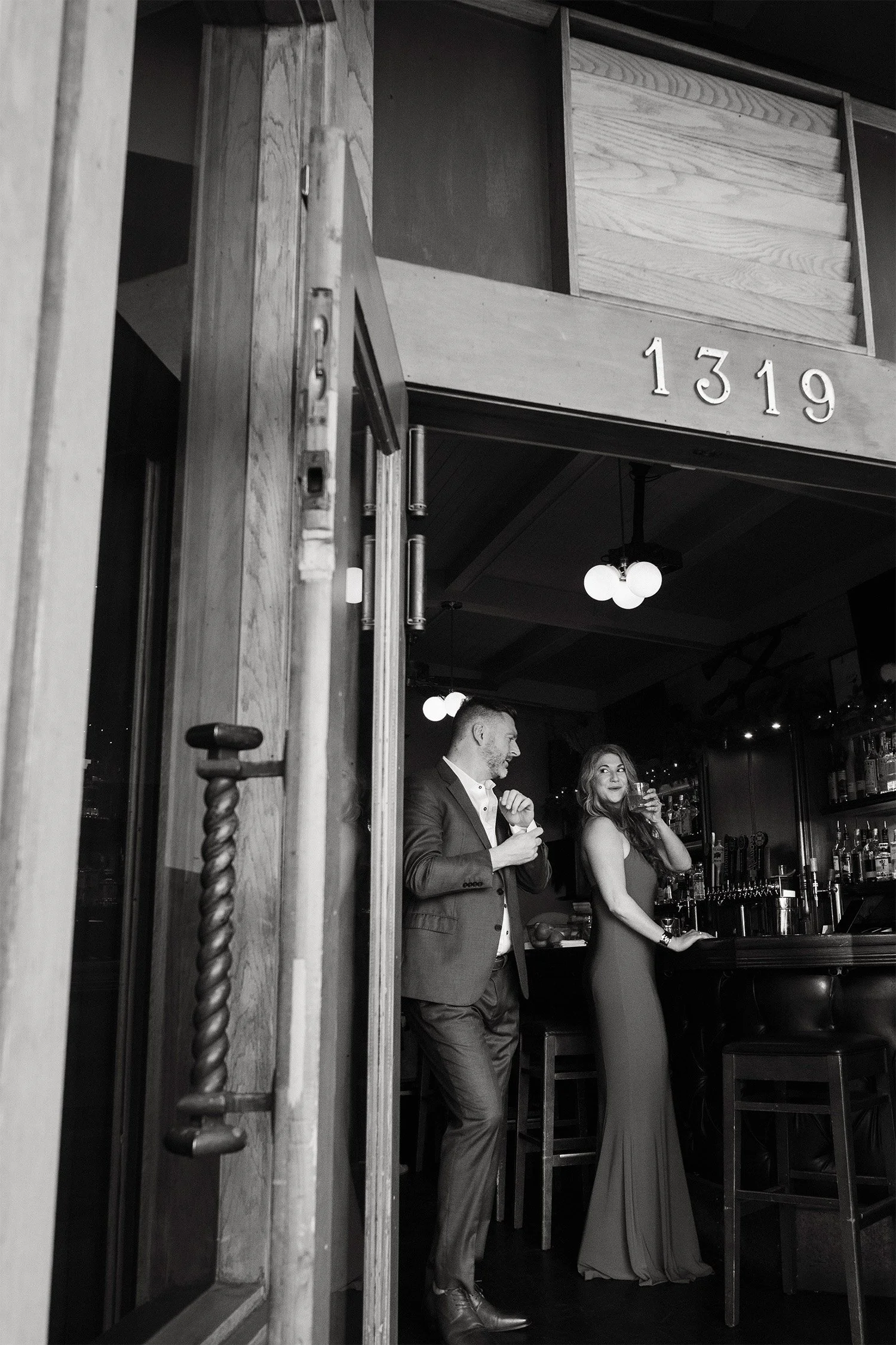 Award-winning engagement photographer in Orange County captures candid black and white moment of couple at vintage bar entrance