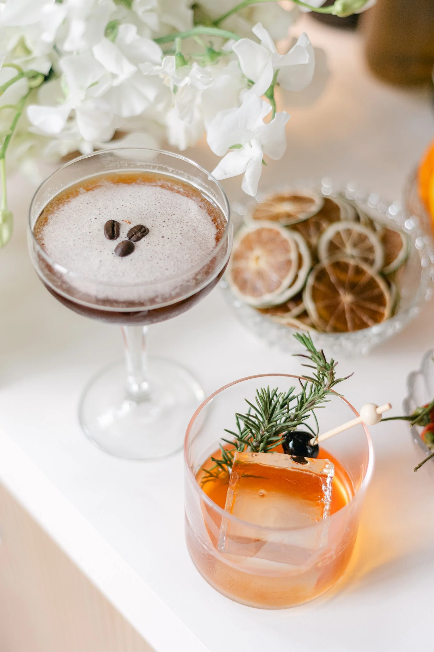 Orange County wedding photographer captures wedding signature espresso martini and old fashioned cocktails styled with white florals at reception bar
