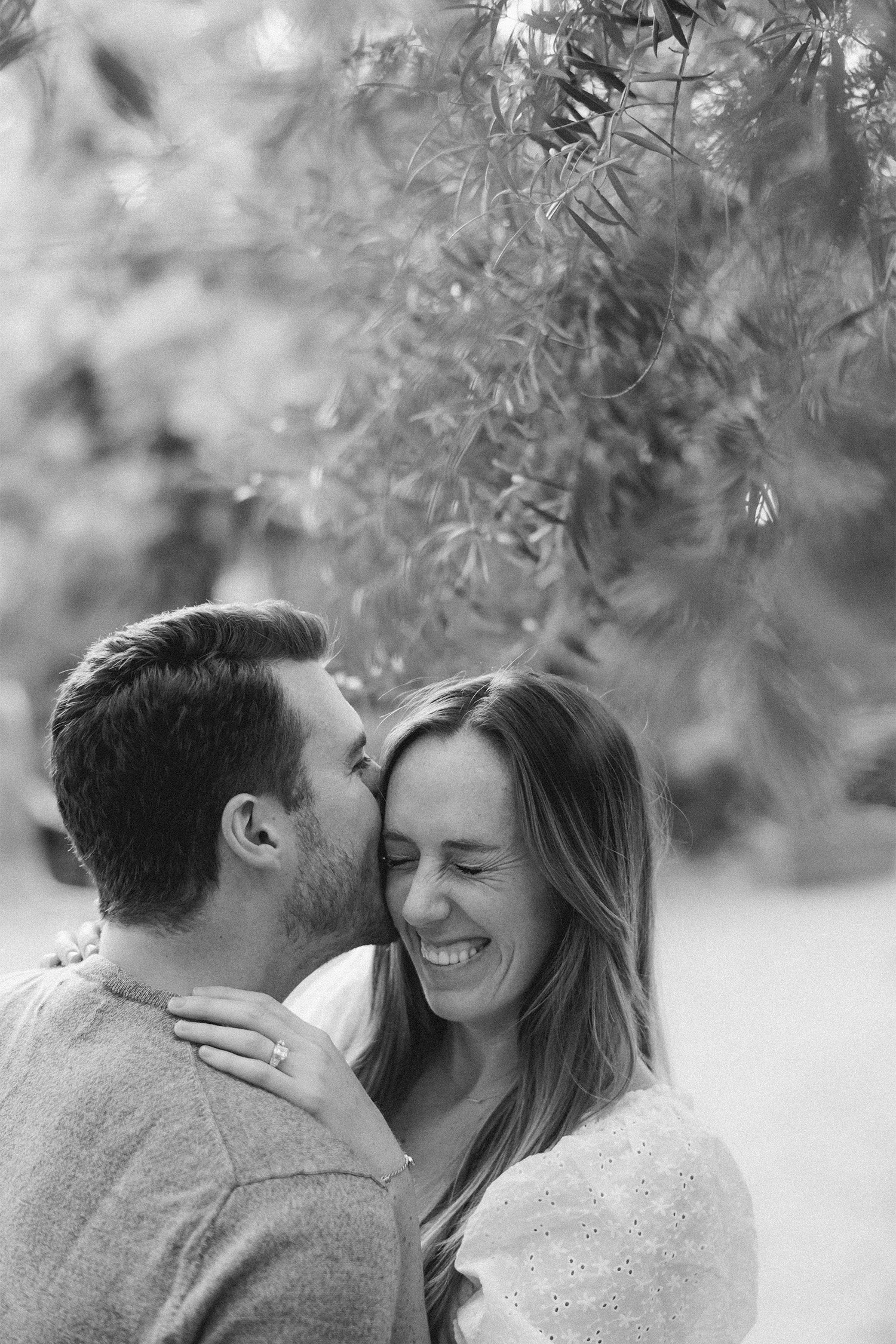 Orange County engagement photographer captures man kissing fiancée's forehead in candid black and white at the Arlington Garden in Pasadena