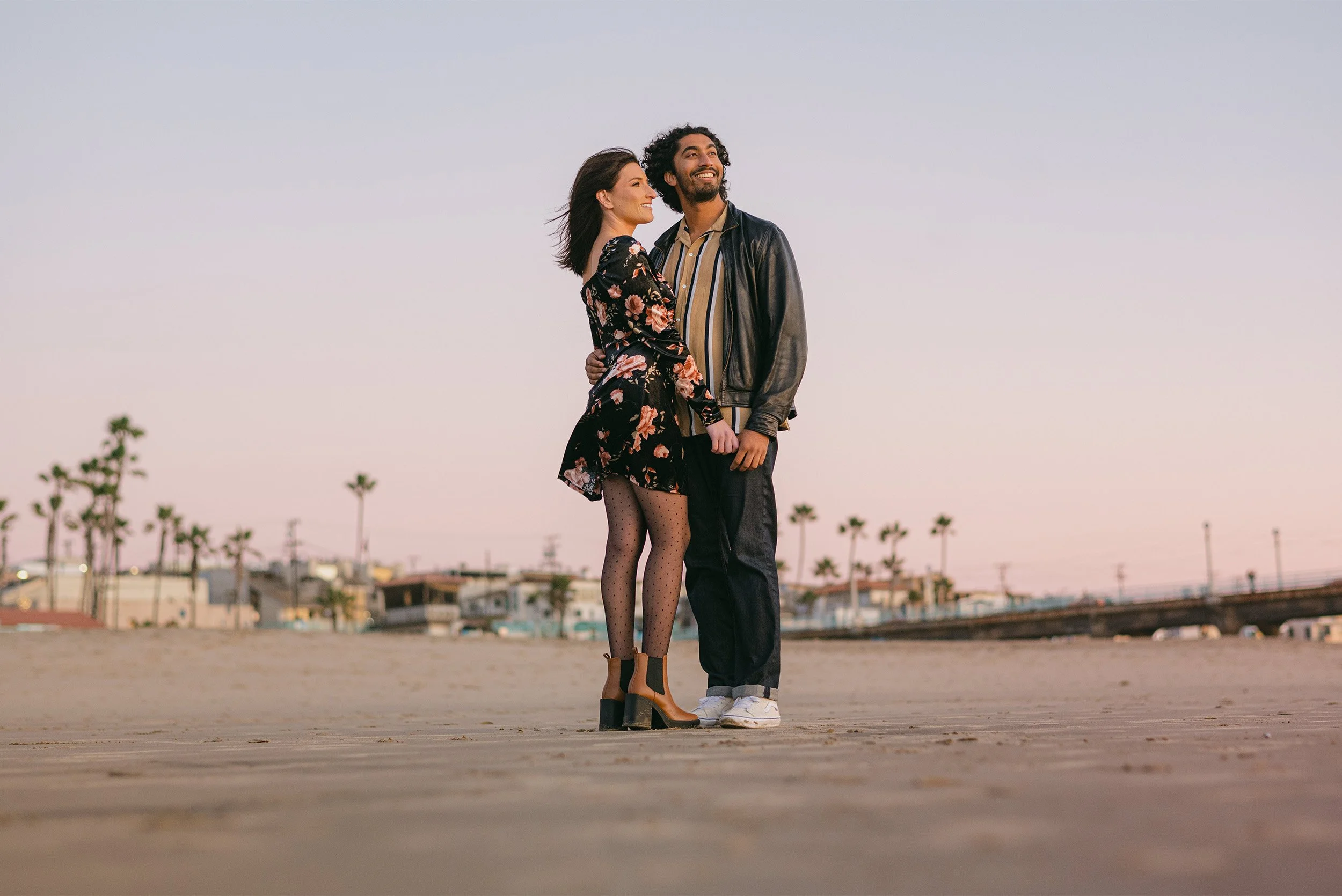 Highly recommended engagement photographer captures couple standing together on Manhattan Beach at dusk