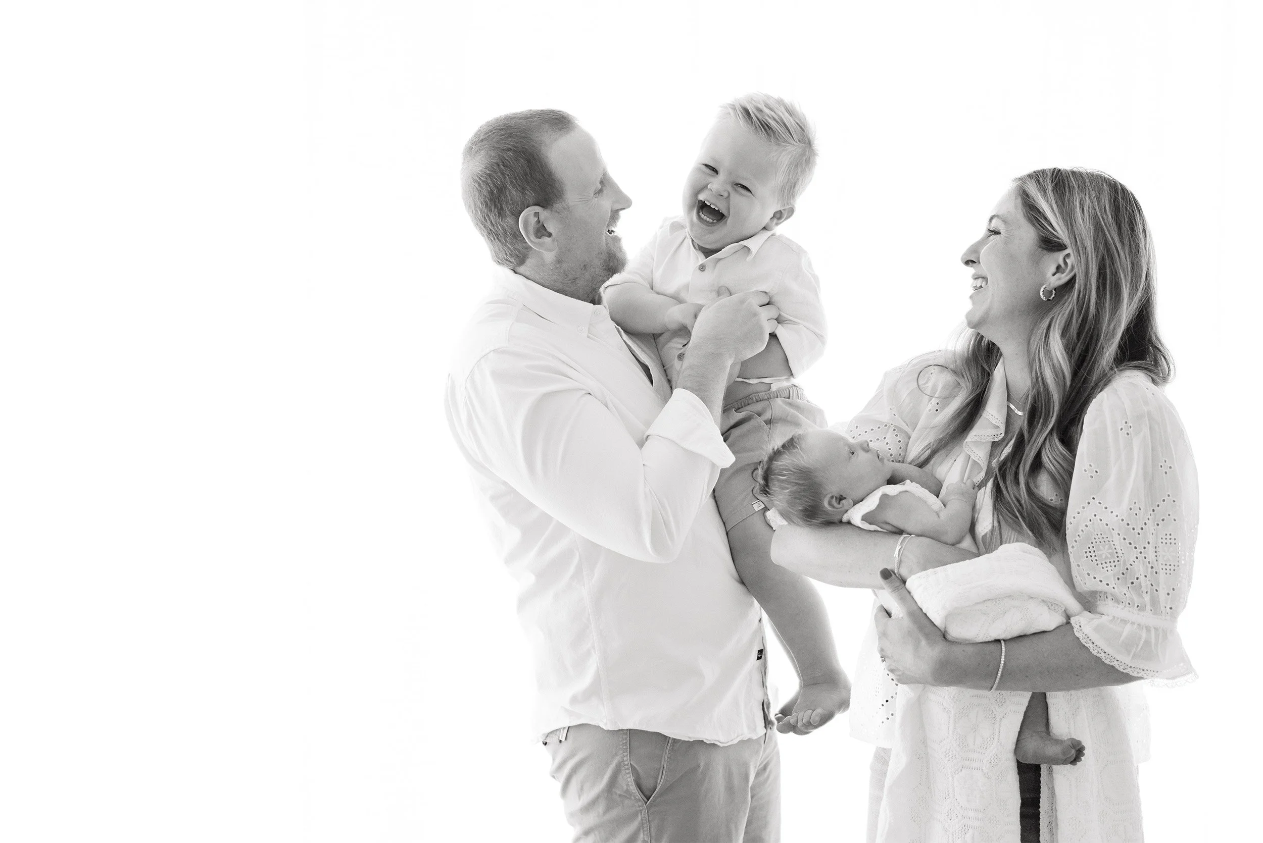 Black and white portrait of parents laughing with toddler and newborn, Orange County baby photographer