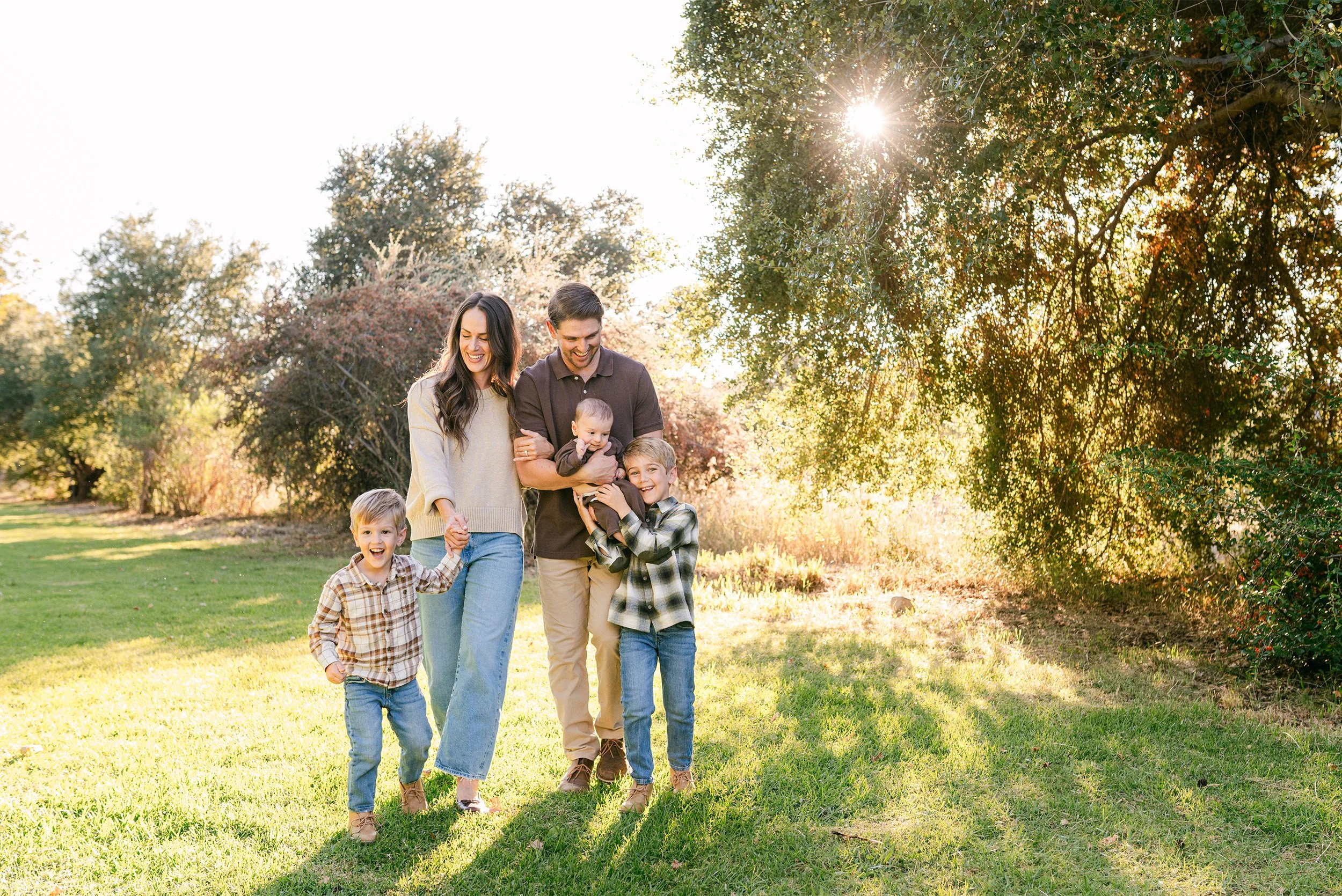 Orange County family photographer captures family of five in sunlit grassy field