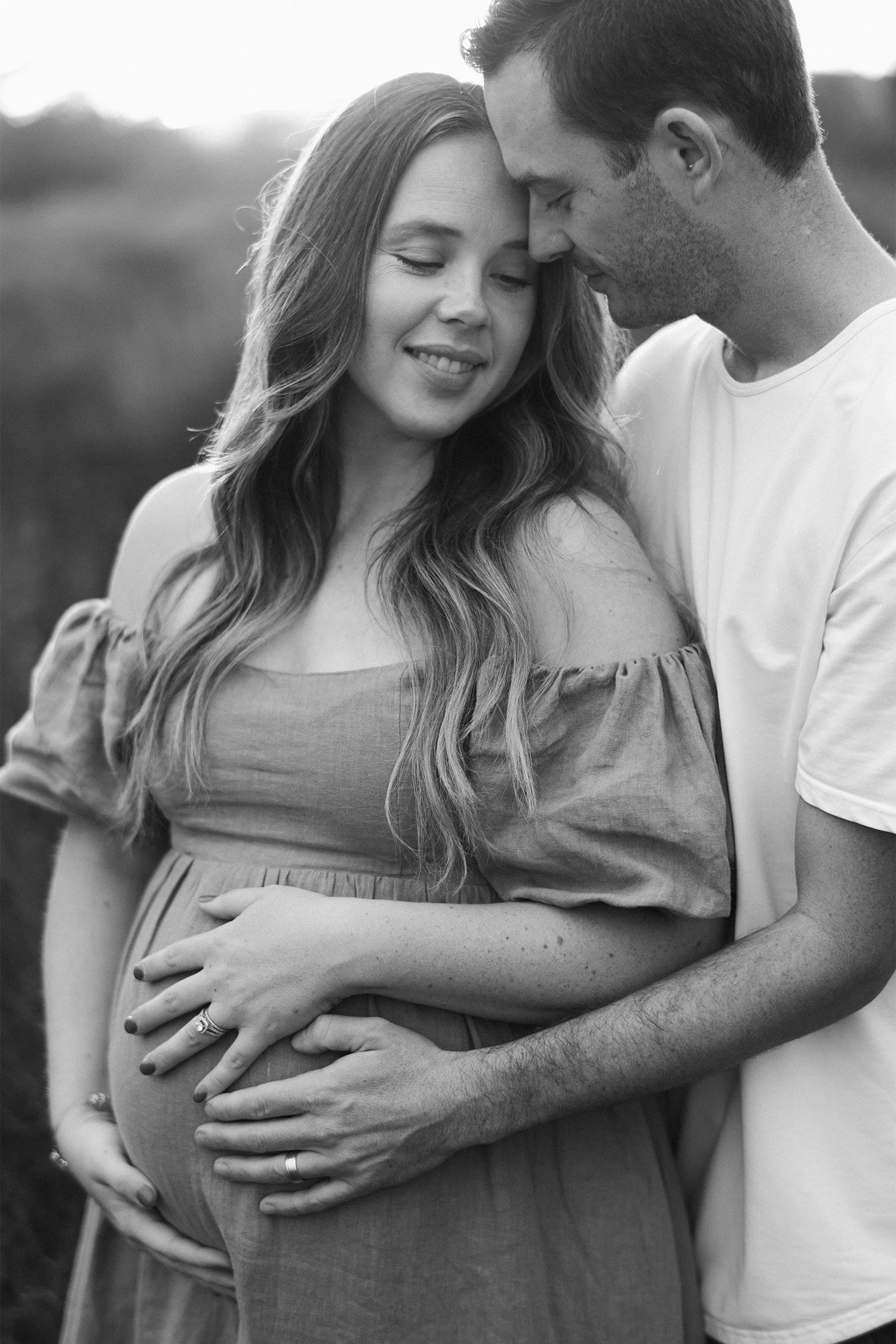 Black and white photo of expecting parents embracing and cradling the baby bump, Highly recommended family photographer in Orange County