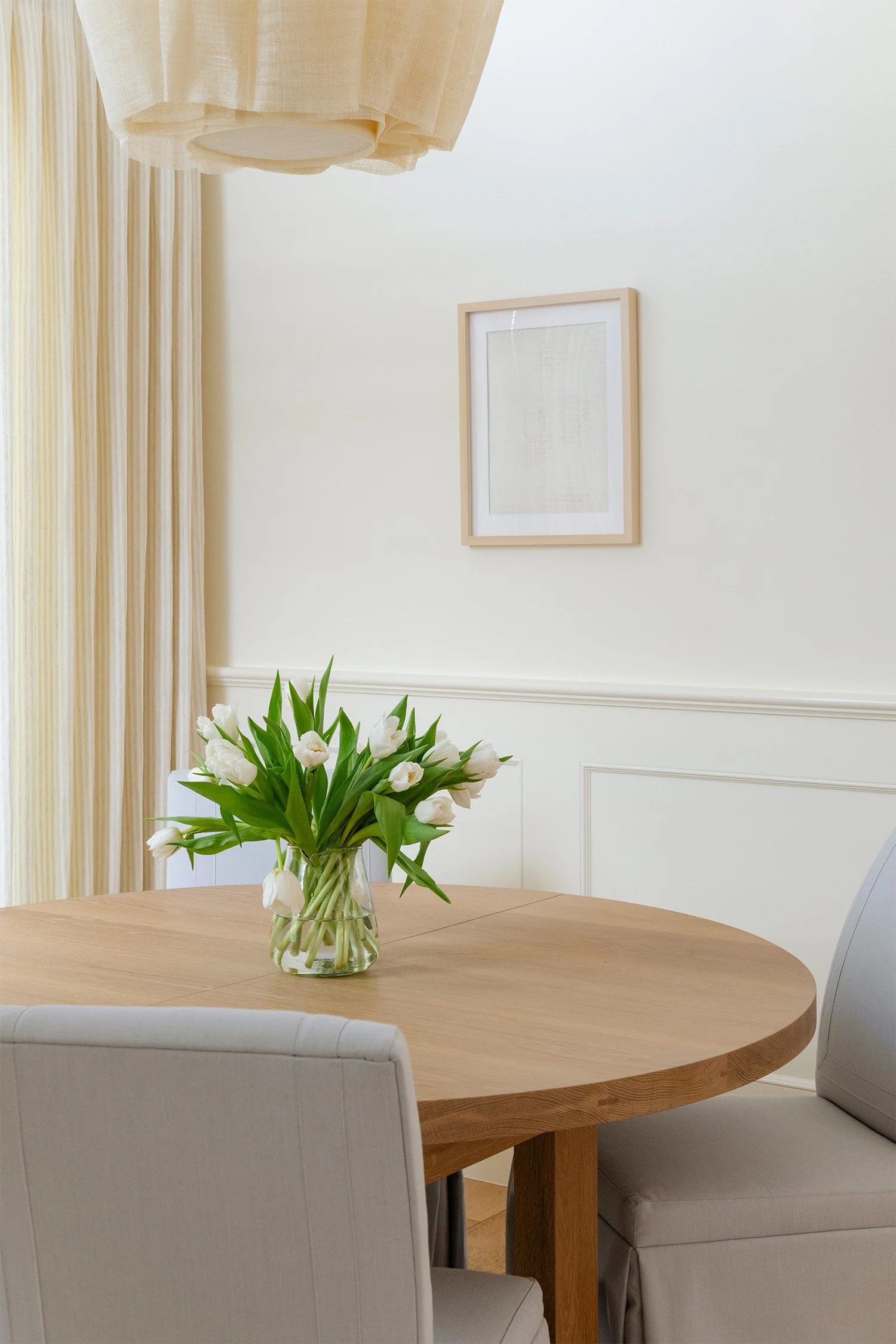 Interior design detail photography of round dining table with white tulip bouquet and framed wall art, Orange County real estate photographer