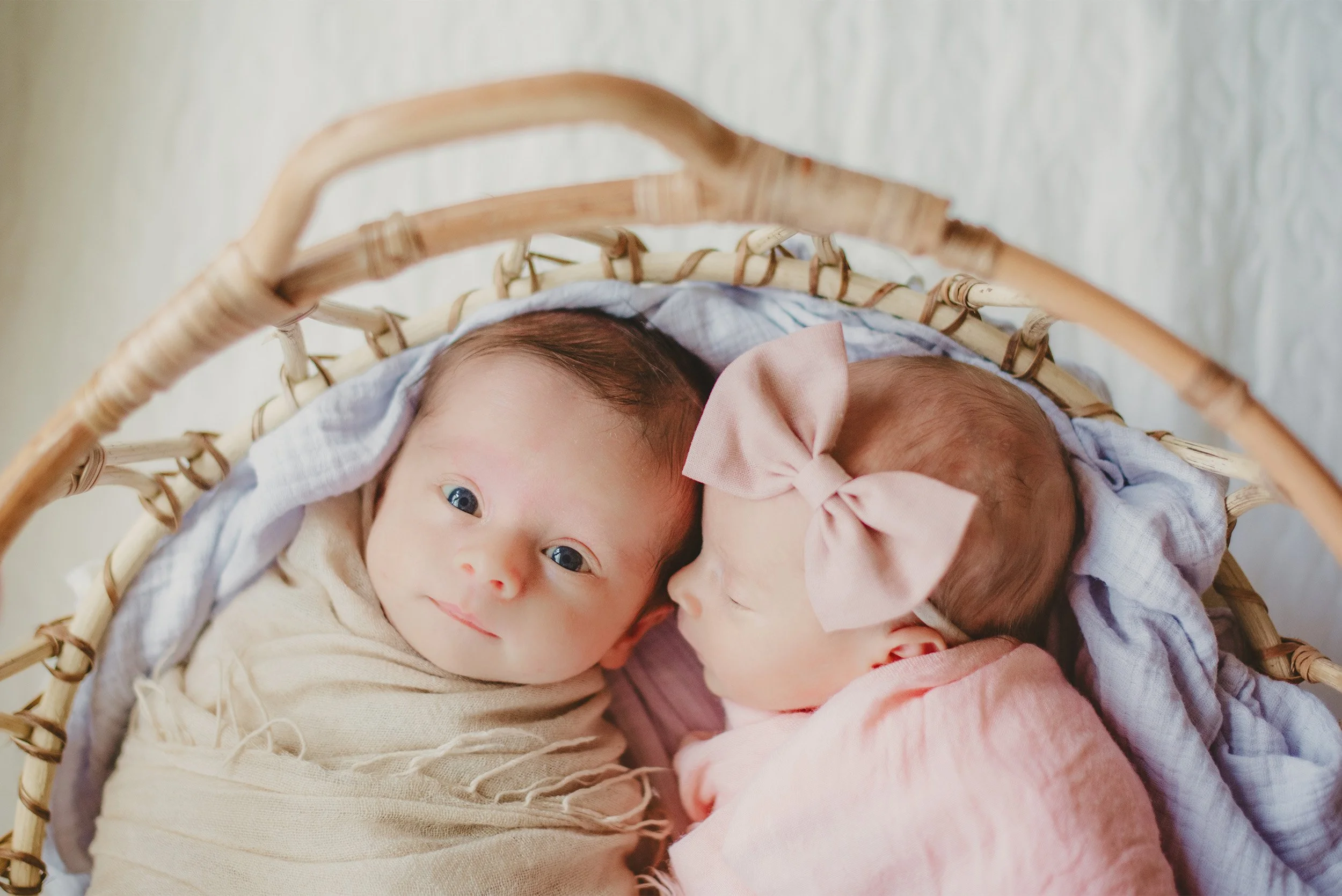 Orange County newborn photographer captures twin newborns nestled together in wicker basket
