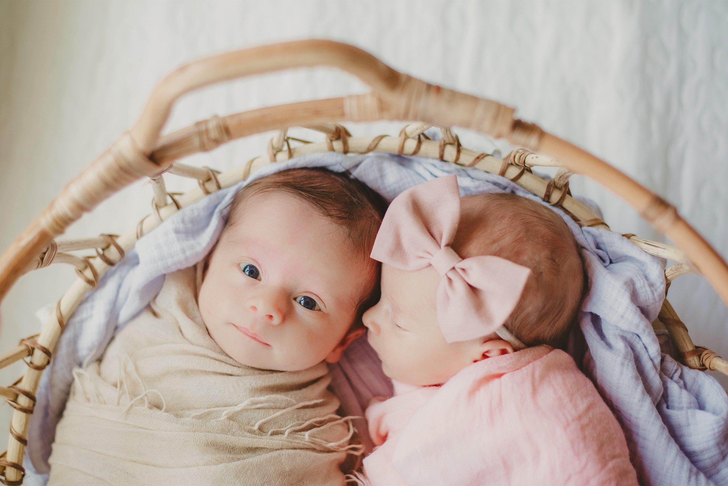 Orange County newborn photographer captures twin newborns nestled together in wicker basket, in home family photos