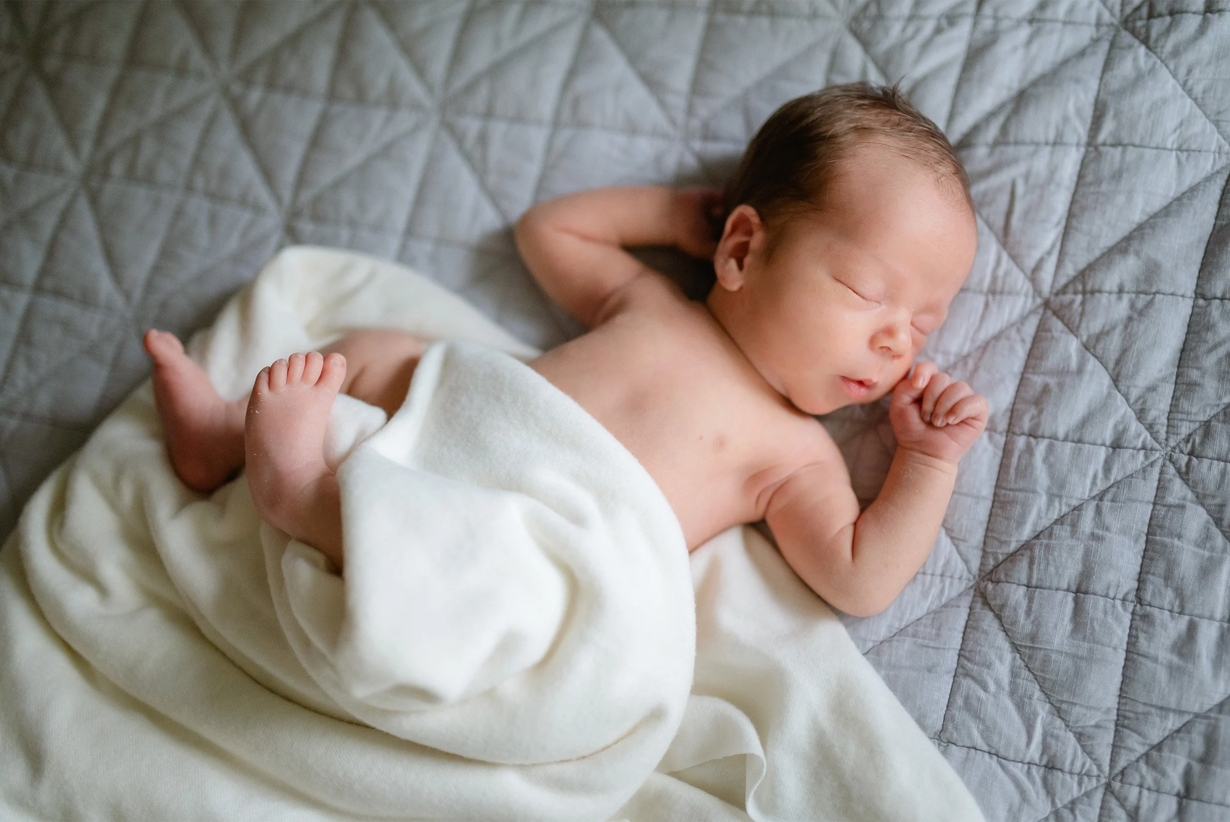 Orange County newborn photographer captures overhead portrait of sleeping newborn wrapped in soft white blanket
