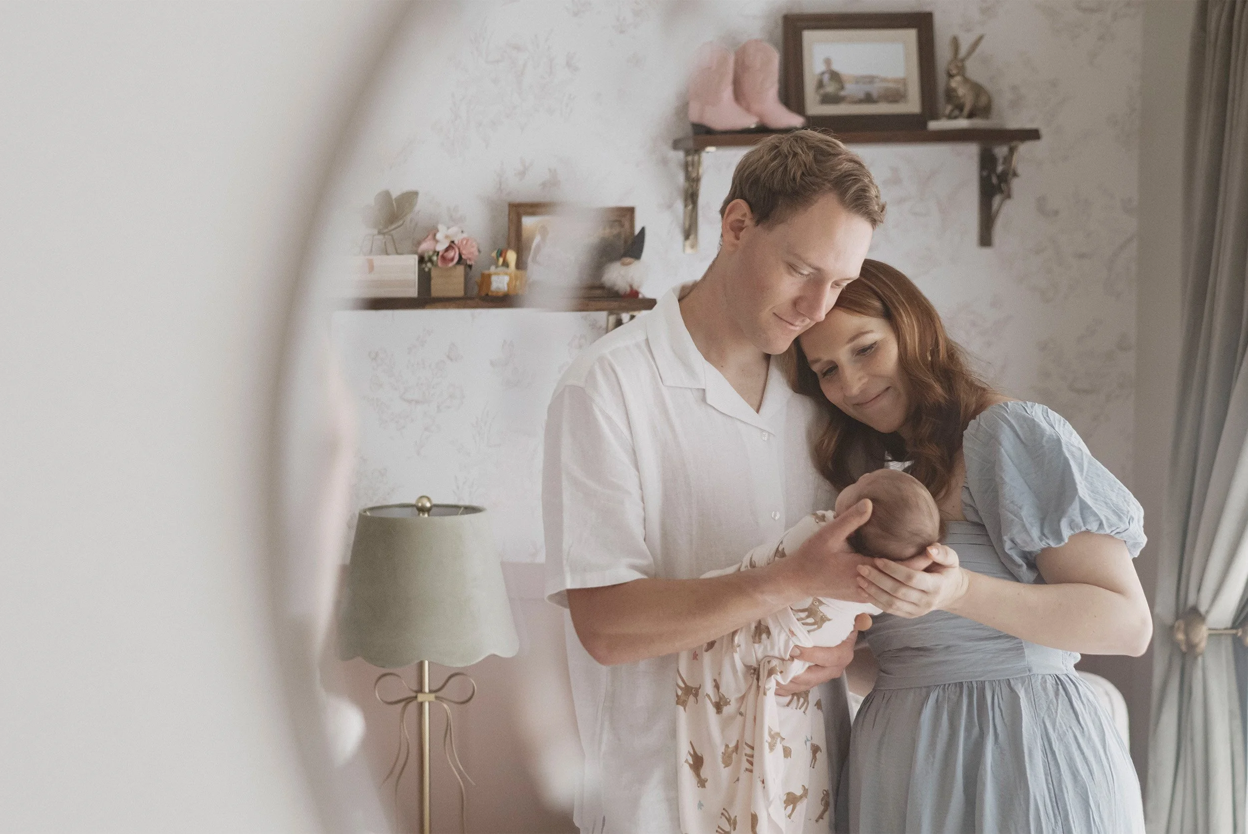 Parents embracing newborn together in nursery mirror reflection at their home, Orange County baby photographer