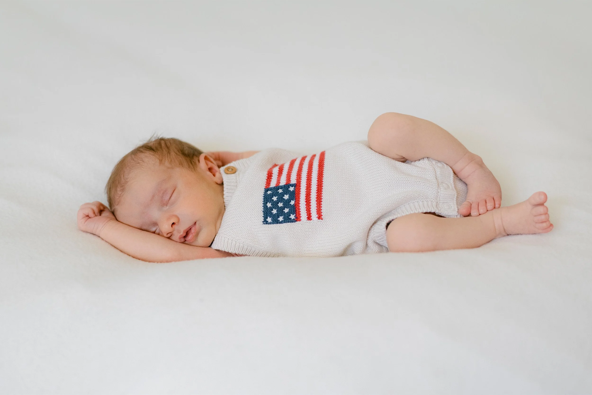 Orange County newborn photographer captures baby sleeping peacefully in American flag knit romper, in home newborn photos