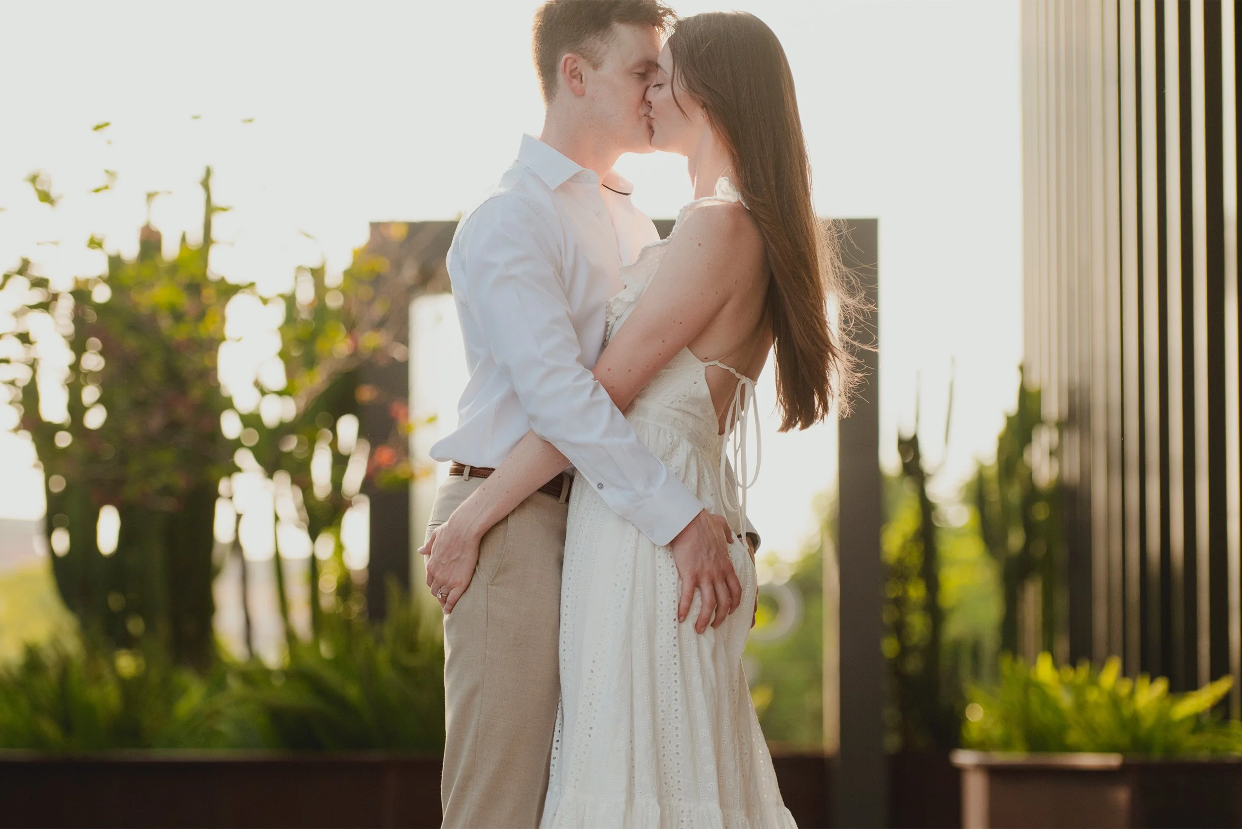 Orange County engagement photographer captures couple sharing a kiss on a sunlit rooftop terrace