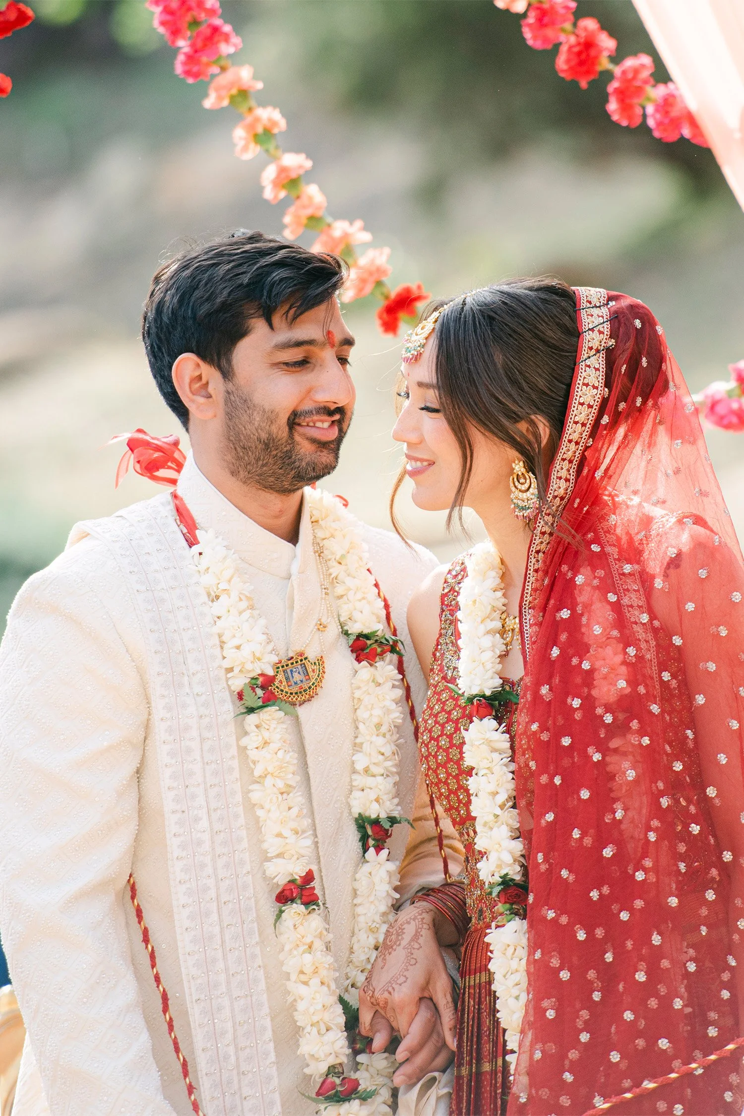 Orange County wedding photographer captures traditional Indian wedding ceremony with bride and groom in floral garlands and red lehenga