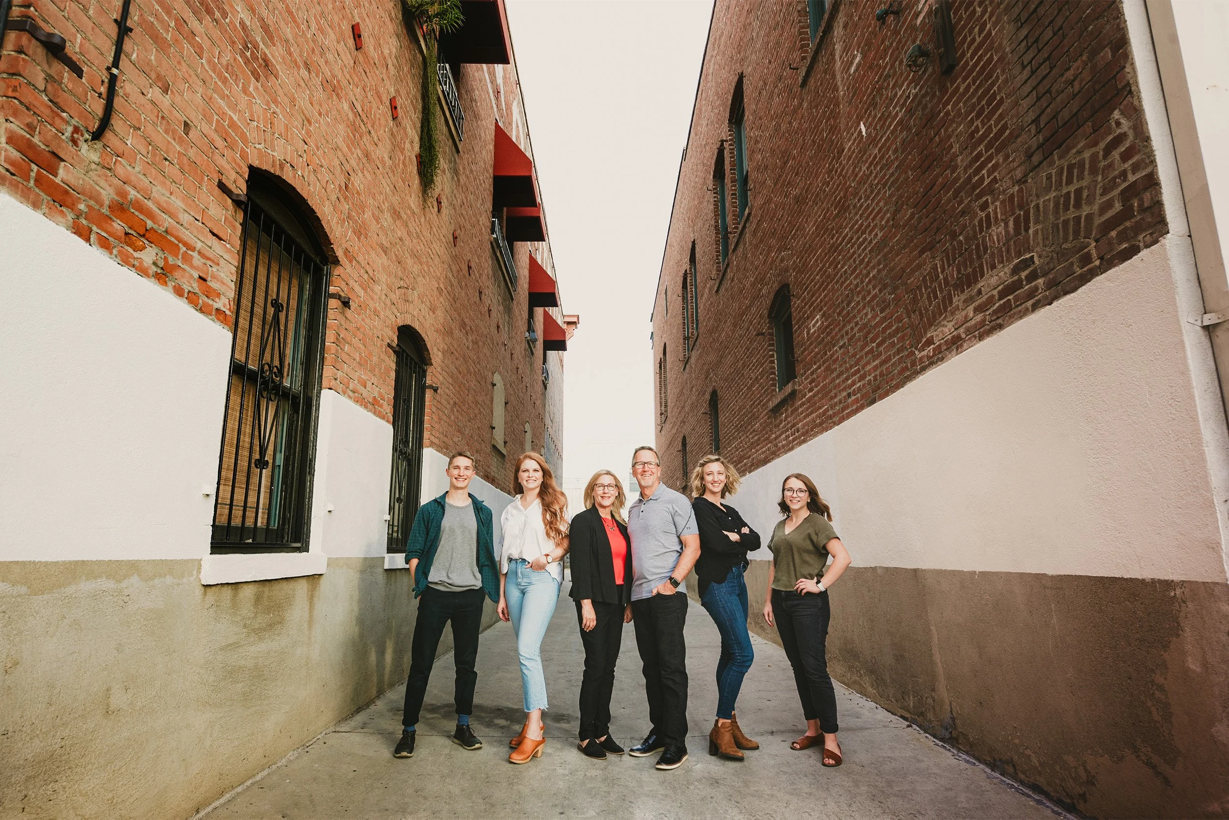 Orange County business photographer captures family business team portrait in industrial brick alley setting in Old Towne Orange