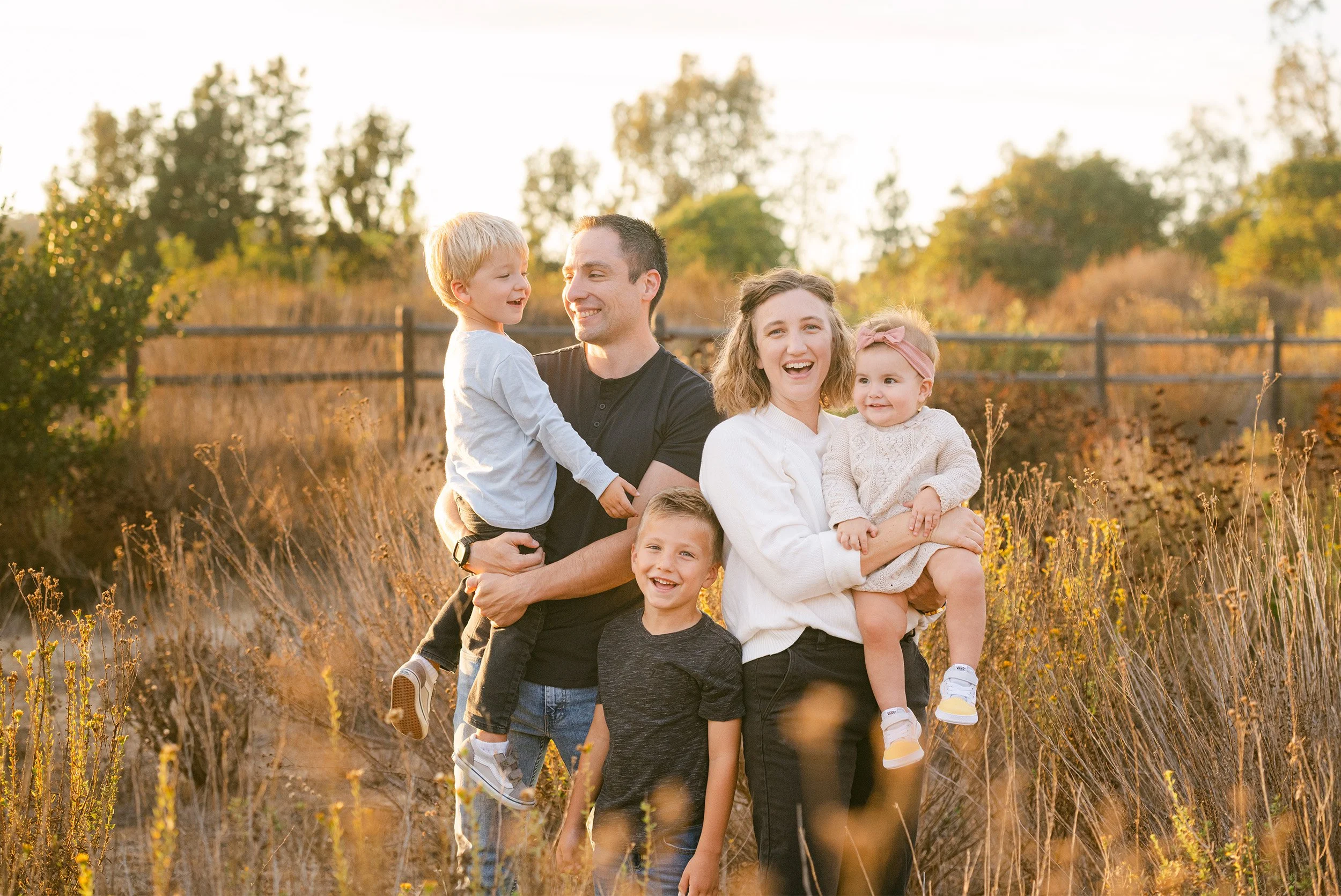 Highly recommended family photographer in Orange County captures laughing family of five in golden field