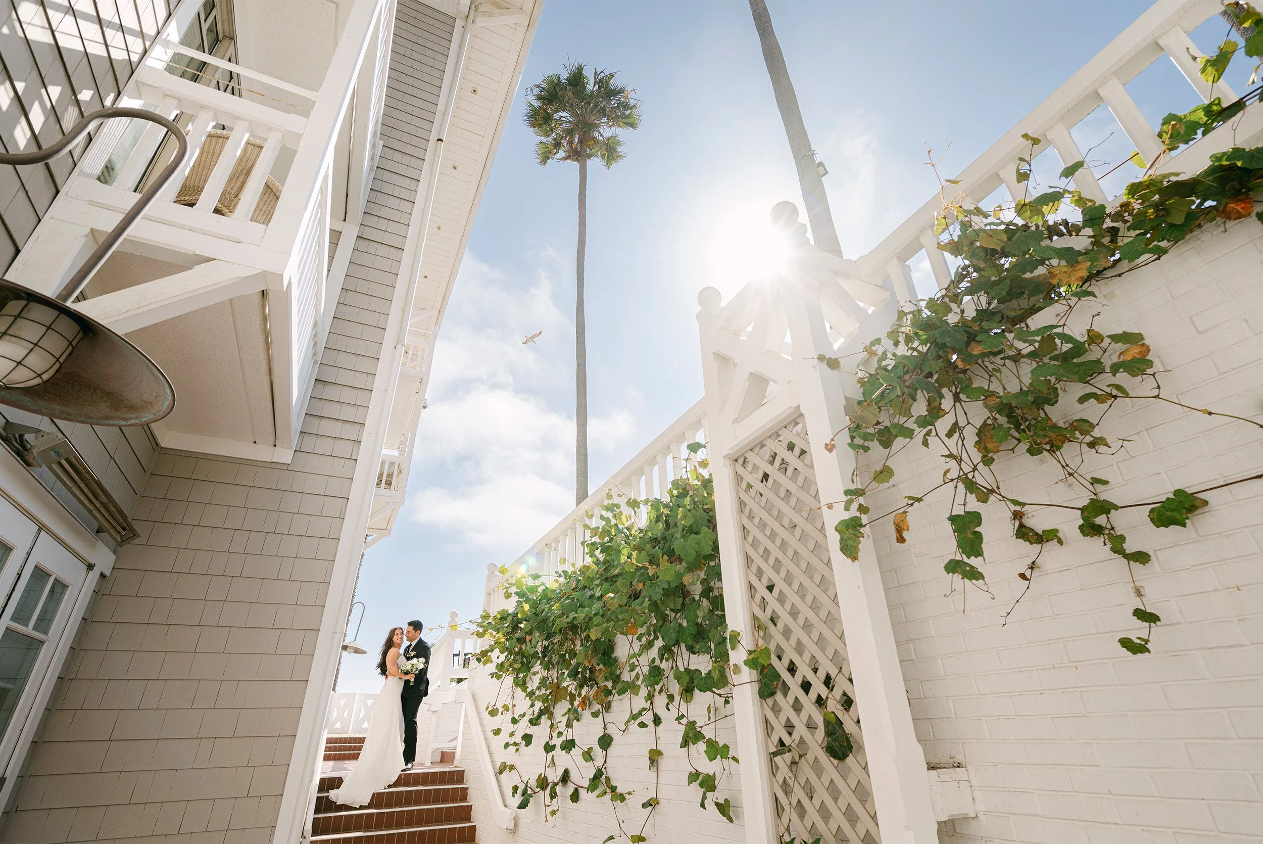 Award-winning wedding photographer in Orange County captures bride and groom on coastal staircase framed by architectural ivy-covered walls at Shutters on the Beach in Santa Monica