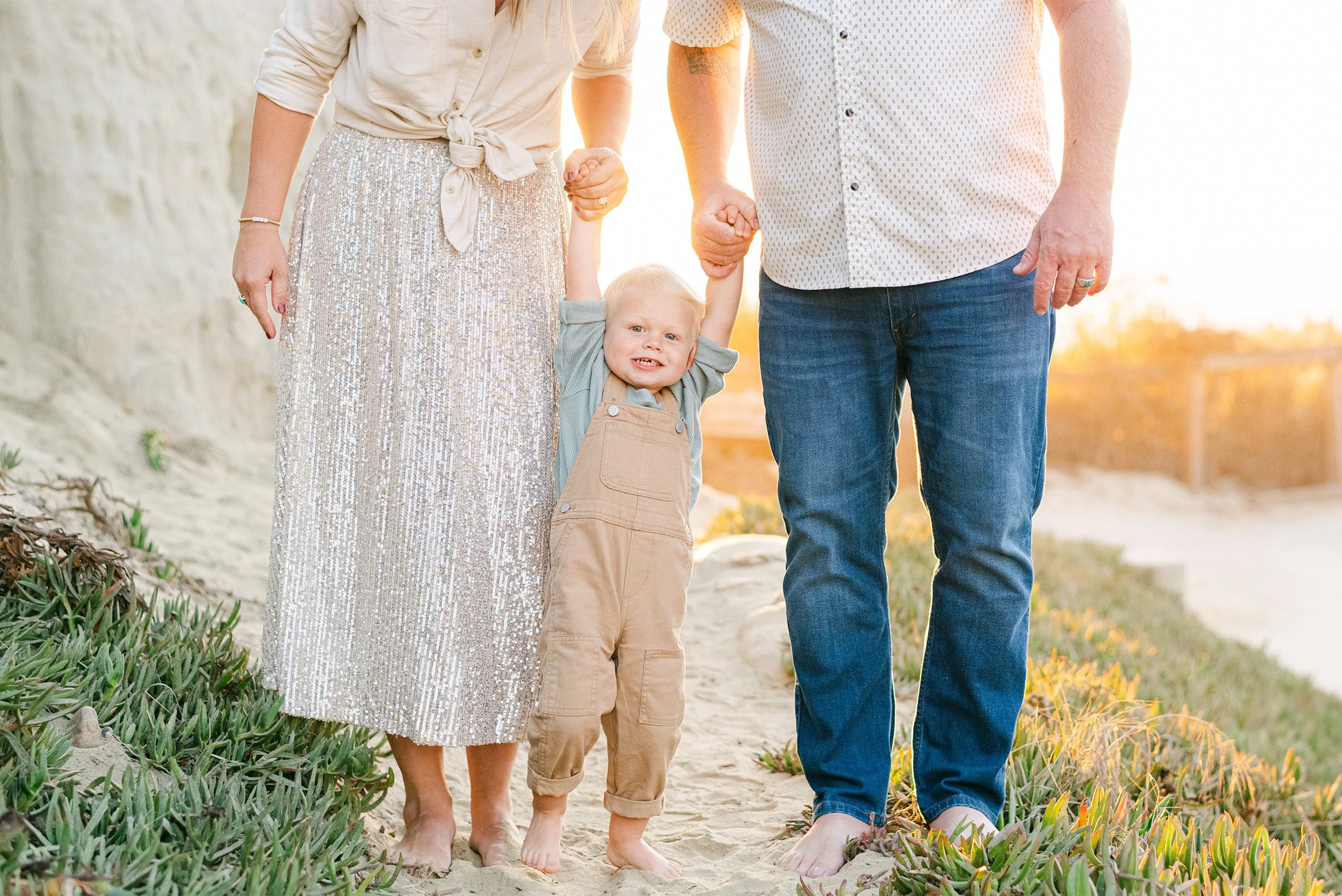Highly recommended family photographer in Orange County captures joyful family moment in golden wildflower field by the beach