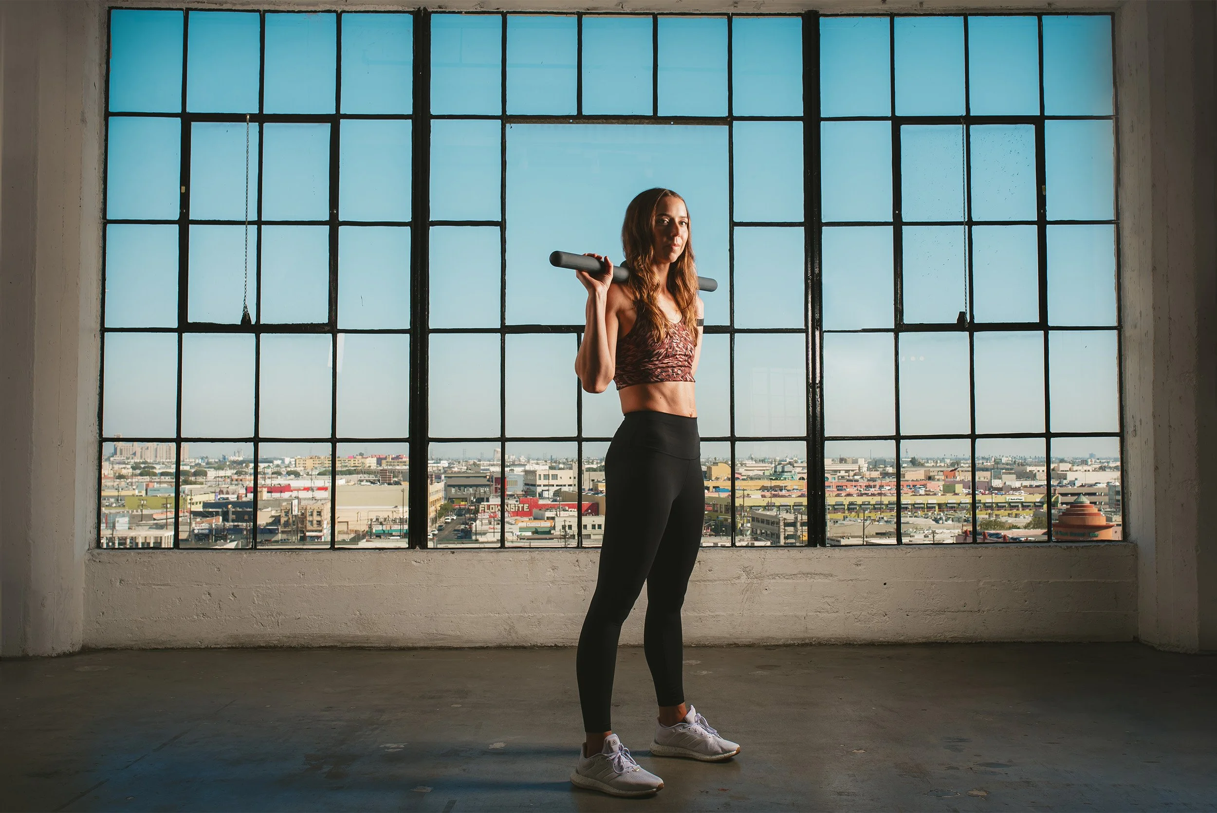 Award-winning brand photographer captures fitness brand portrait in industrial loft with skyline backdrop, Orange County brand photographer