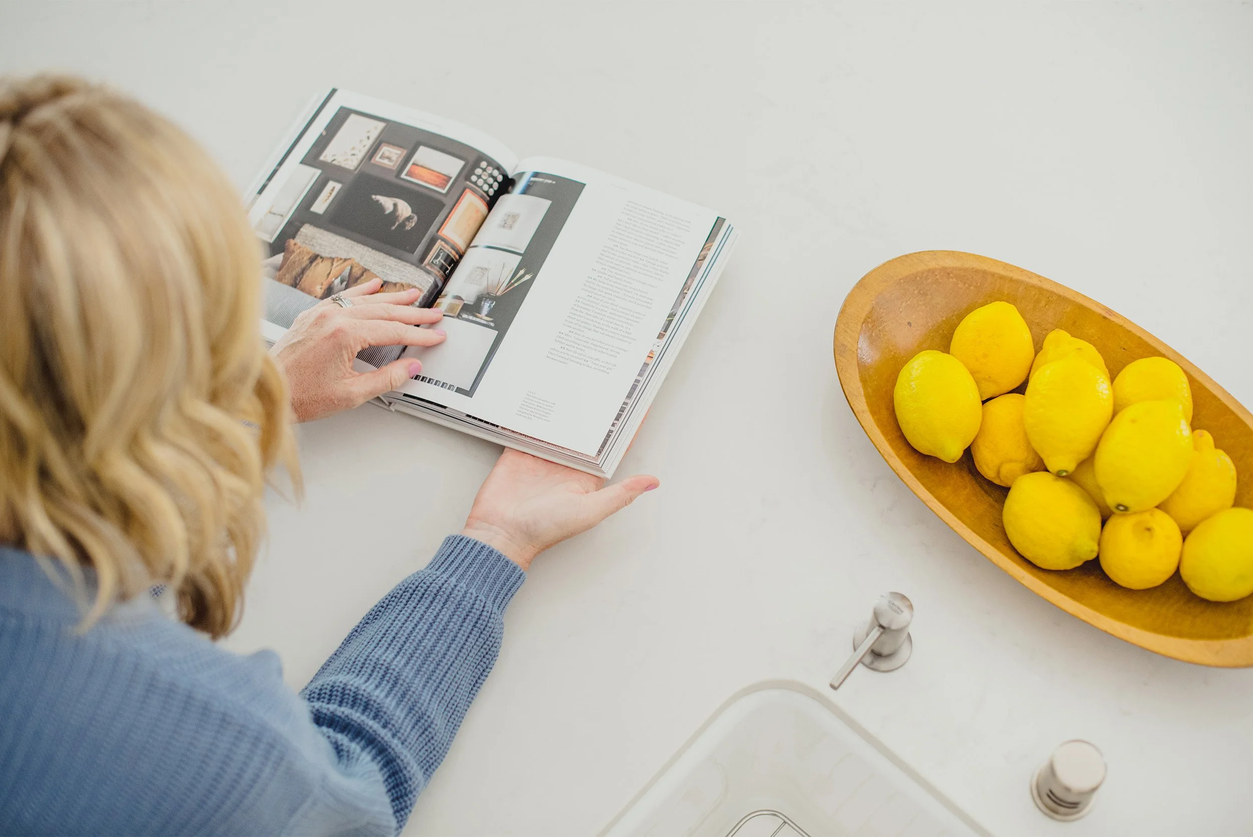 Lifestyle brand photography of woman reading interior design book beside bowl of fresh lemons, Orange County brand photographer
