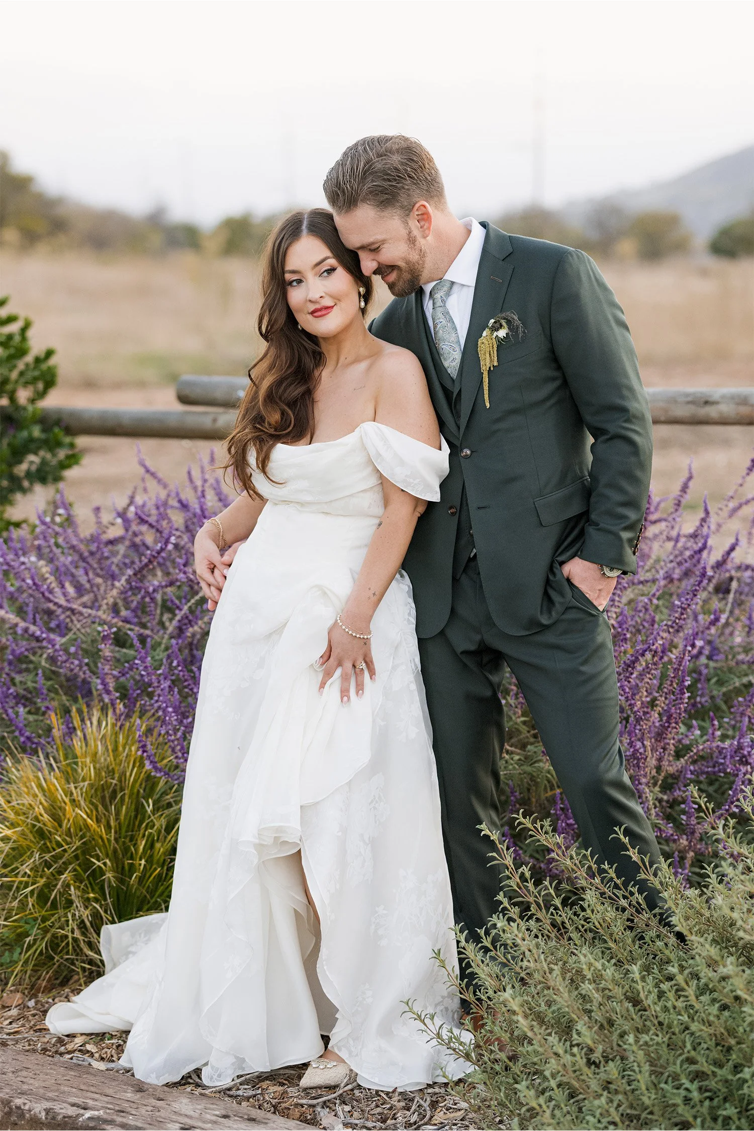 Bride and groom embracing in front of purple wildflowers at golden hour at The Swanner House in San Juan Capistrano, Orange County wedding photography