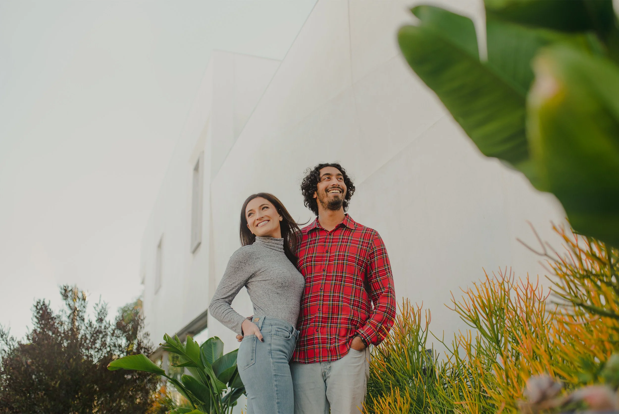 Award-winning engagement photographer in Manhattan Beach captures couple smiling together surrounded by lush tropical greenery