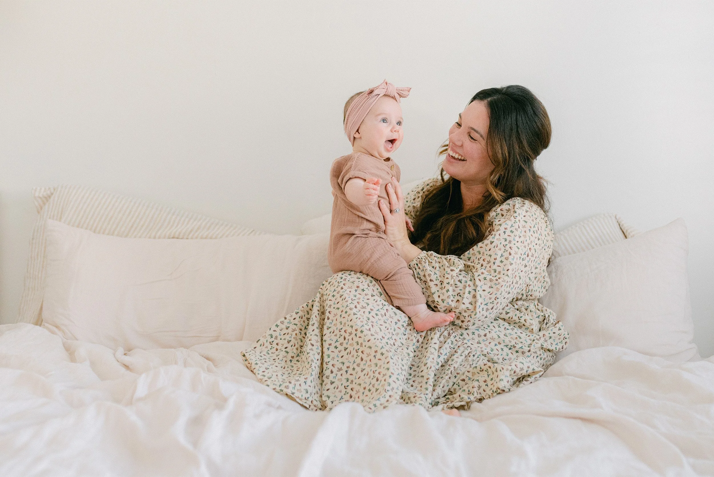 Highly recommended family photographer in Orange County captures mother and baby laughing together on bed