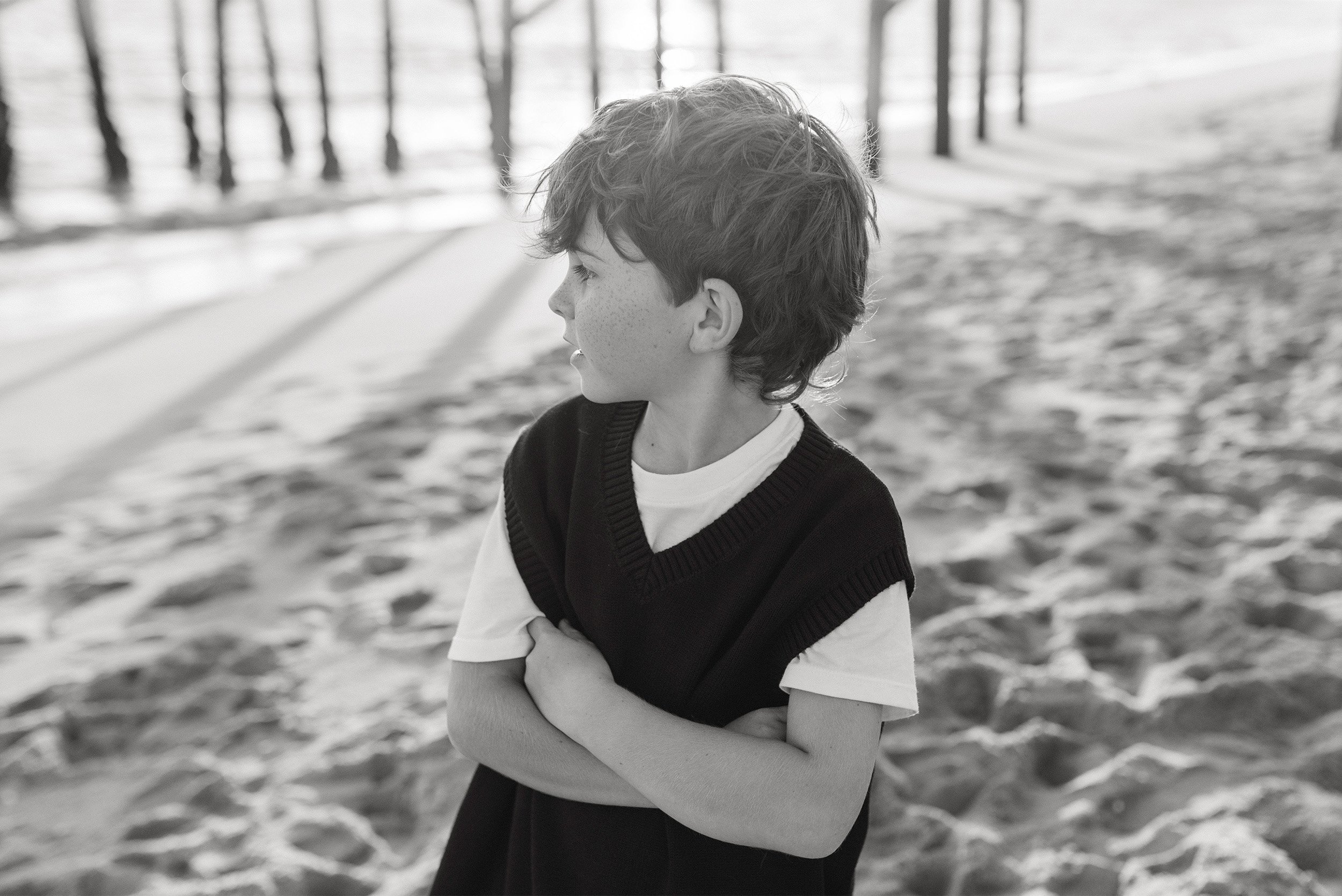 Black and white beach portrait of young boy in sweater vest in Newport Beach, Orange County family photographer