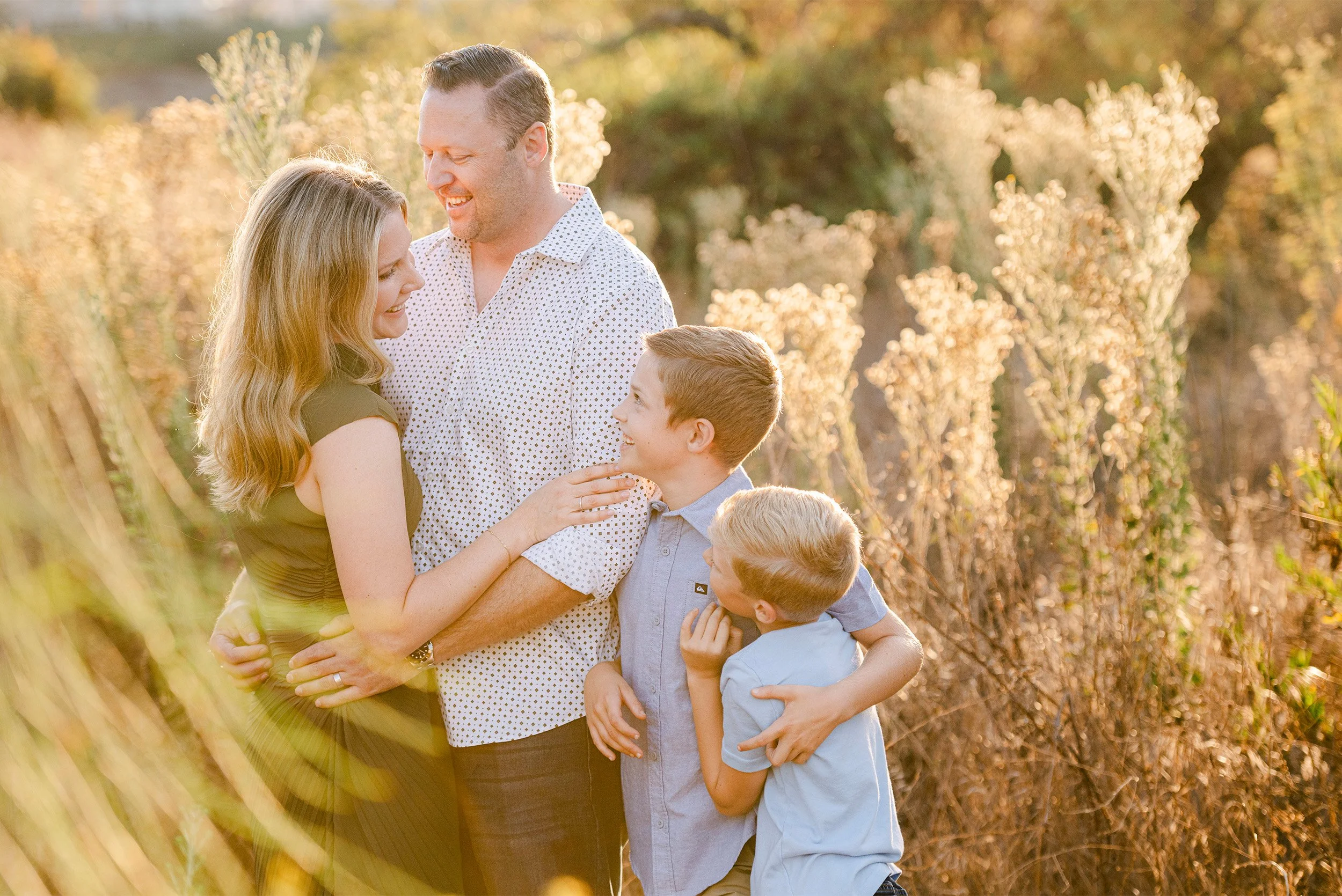 Orange County family photographer captures warm embrace between parents and sons in golden field
