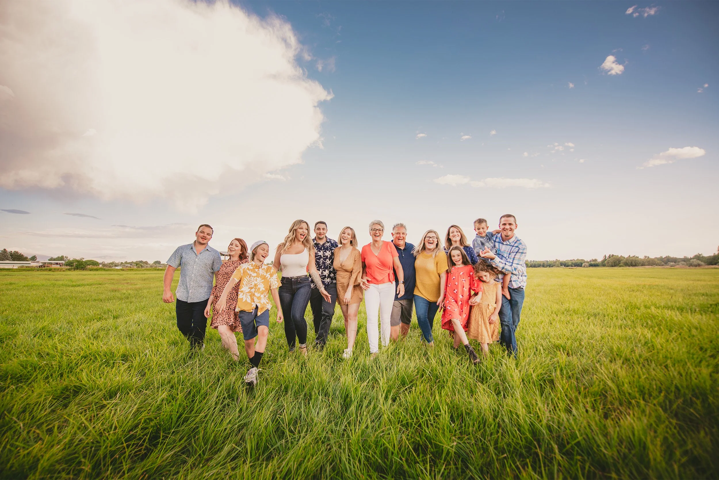 Orange County family photographer captures joyful extended family portrait walking through green grass field