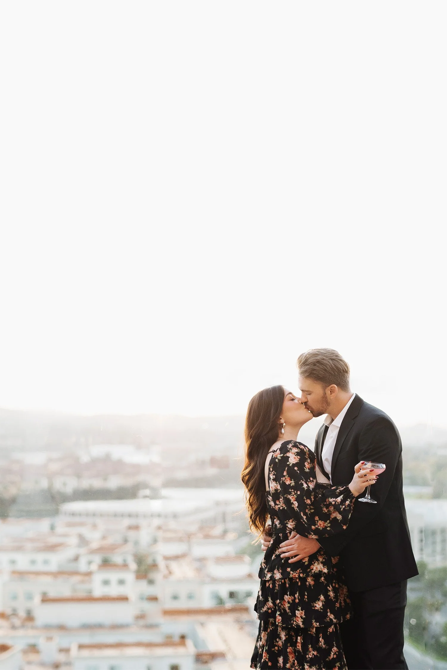 Highly recommended engagement photographer in Orange County captures rooftop kiss at golden hour