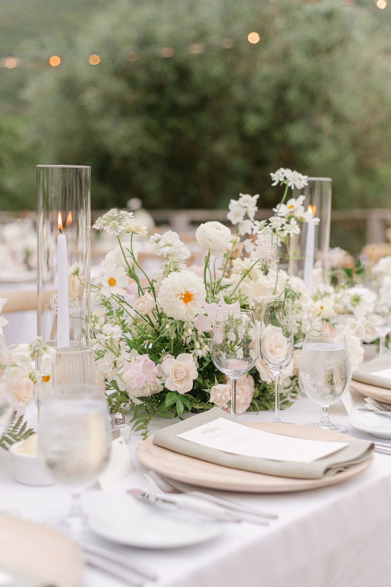 Wedding photographer in Orange County captures romantic white floral centerpiece with candlelight at elegant reception table, The Ranch at Laguna Beach wedding venue