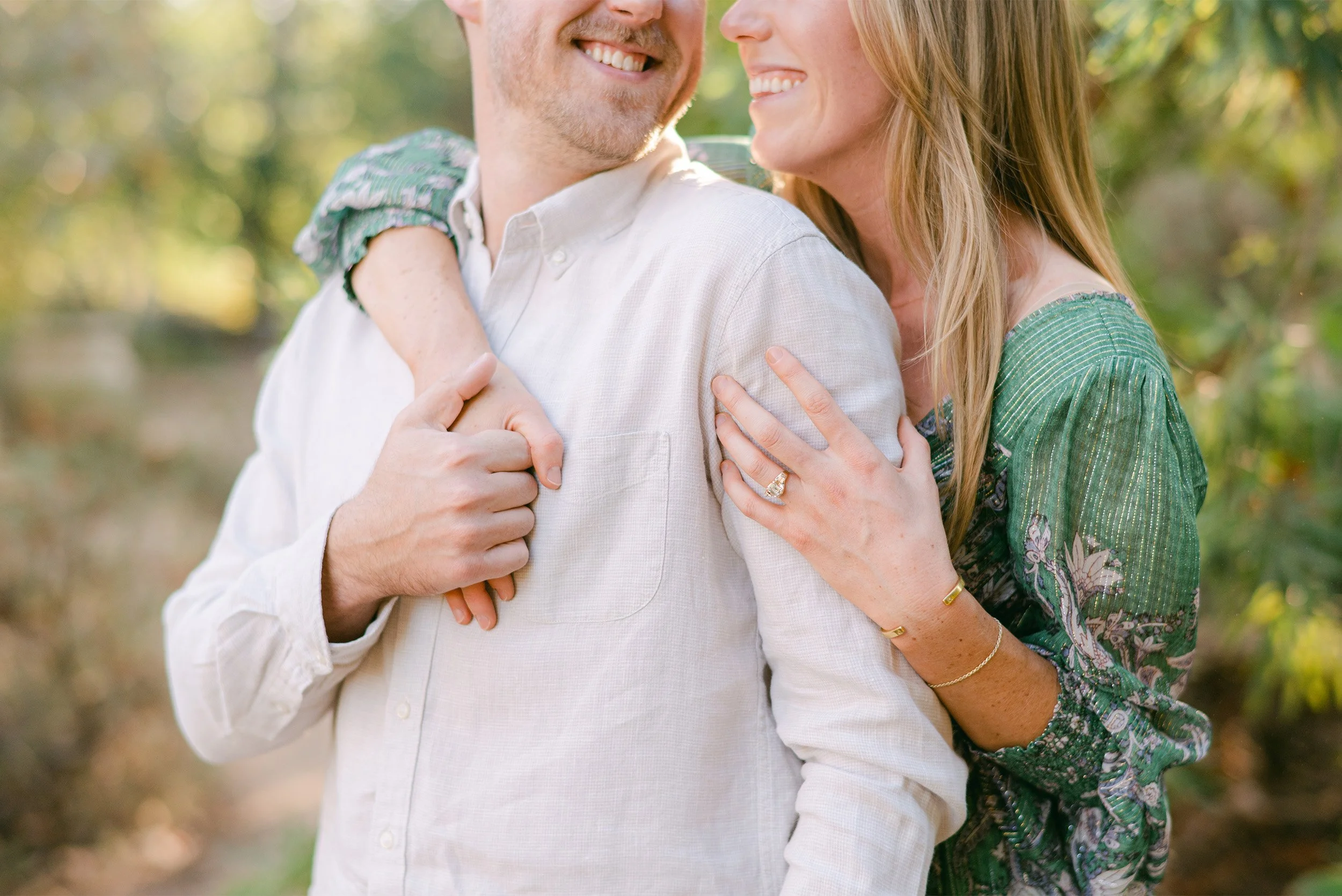 Close-up of engagement ring on bride's hand as couple embraces, highly recommended engagement photographer Orange County