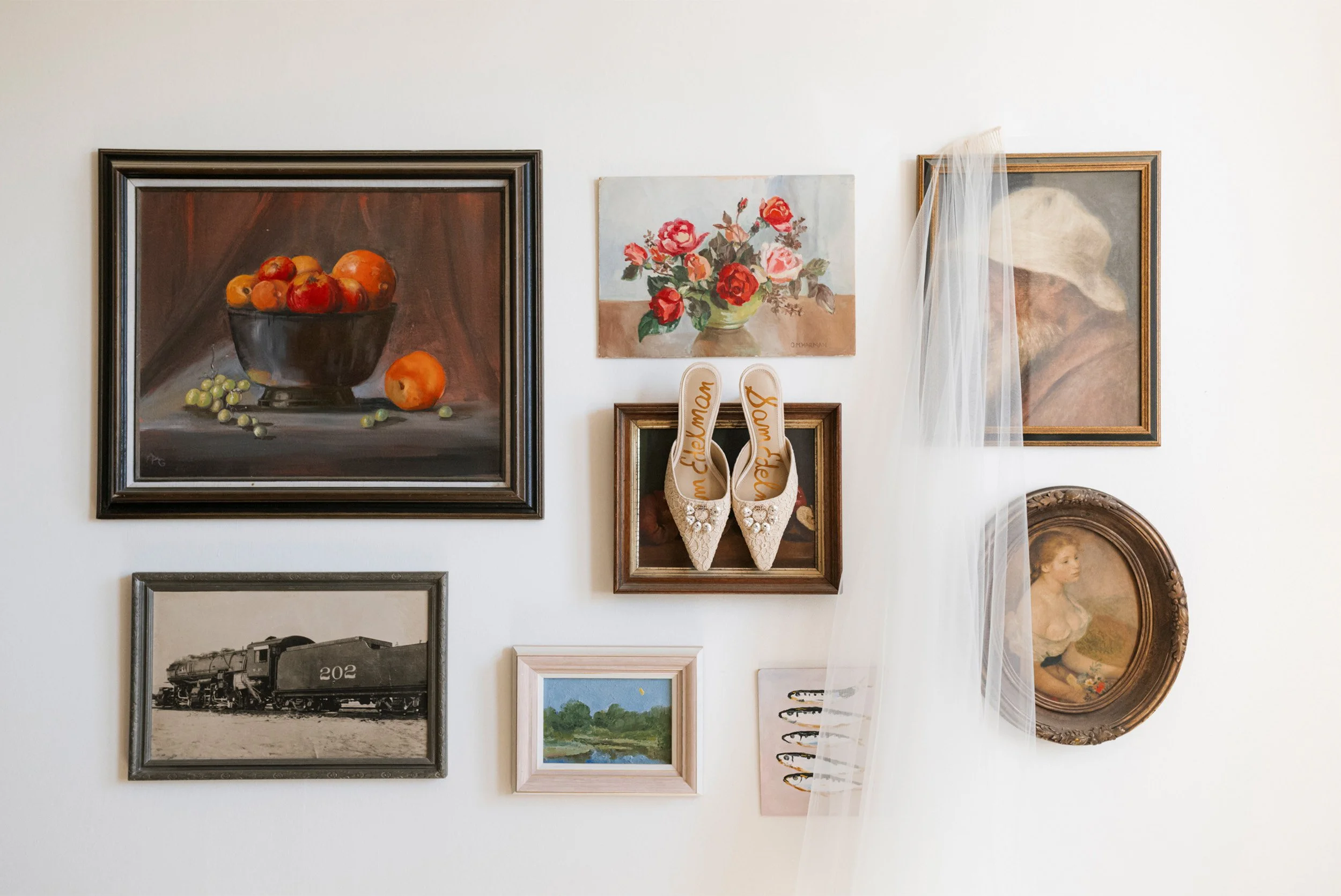 Orange County wedding photographer captures bride's wedding shoes and veil displayed among vintage framed art at Swanner House Wedding Venue in San Juan Capistrano