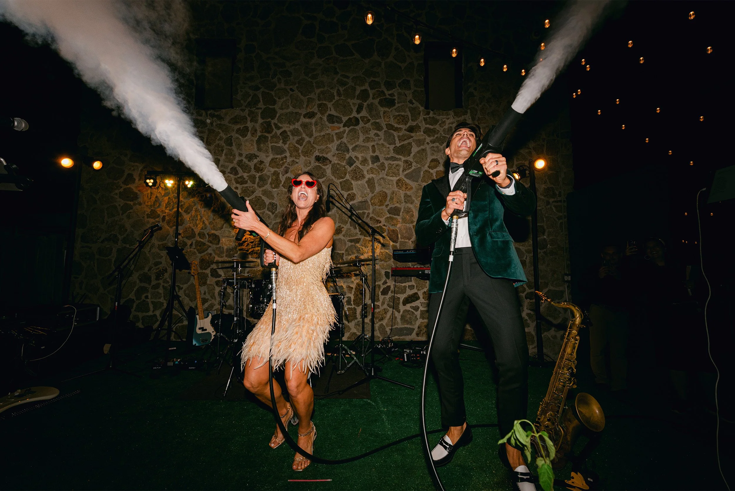 Bride and groom shooting fog cannons on stage at wedding reception at Cielo Farms Malibu, live band in background