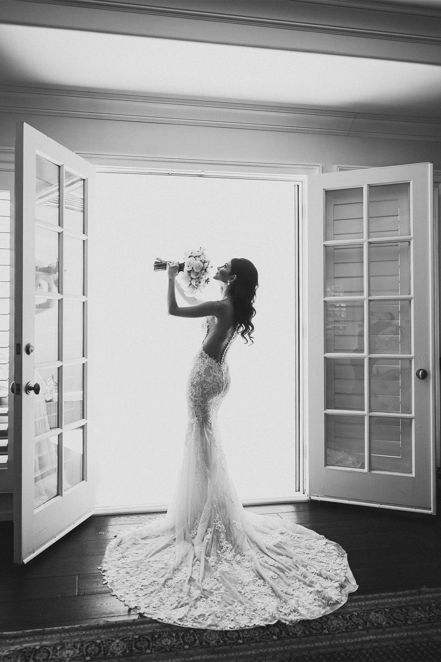 Bride in strapless lace gown silhouetted against sheer curtains at San Ysidro Ranch, black and white bridal portrait