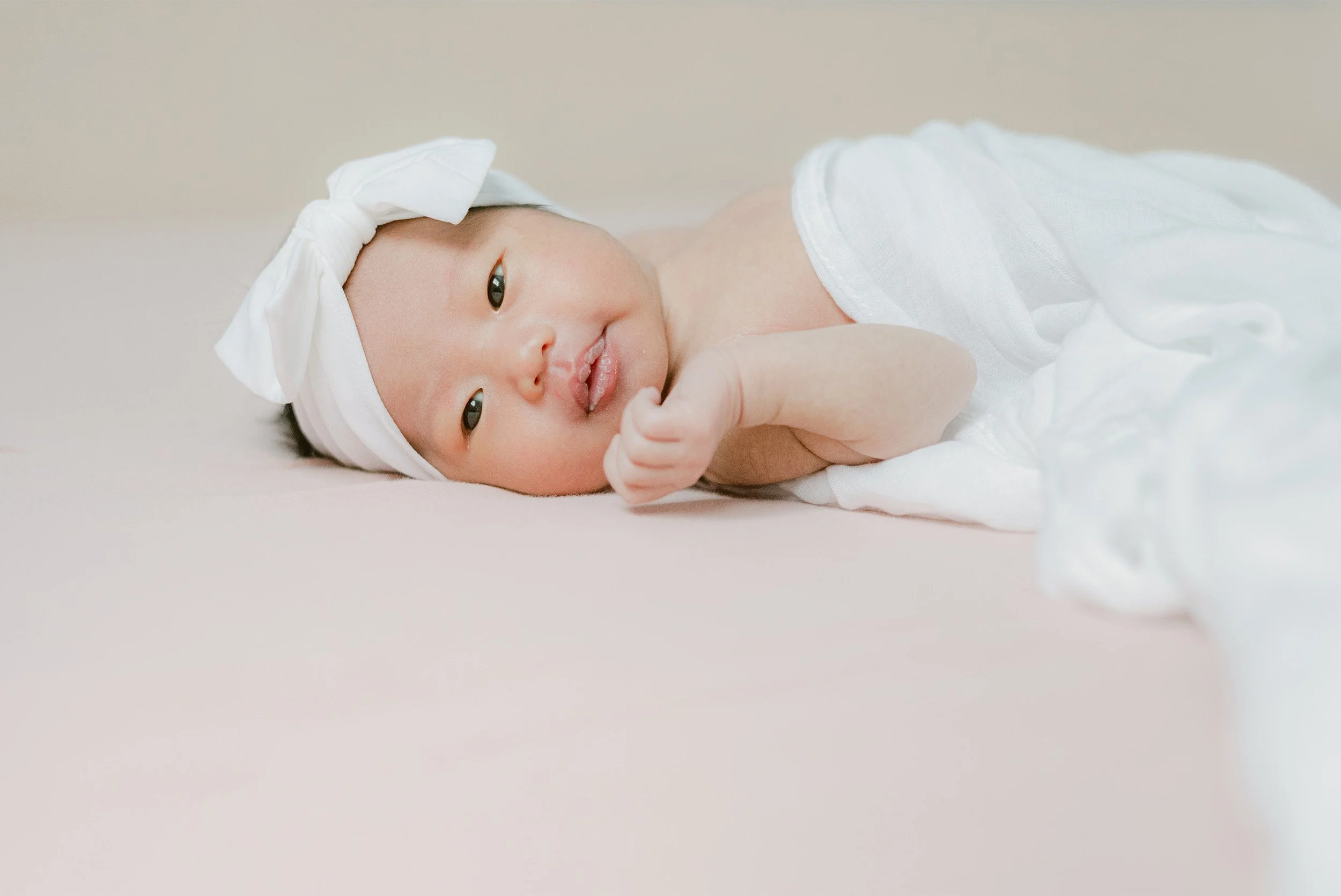 Close-up of newborn in white bow headband looking at camera, Orange County newborn photographer