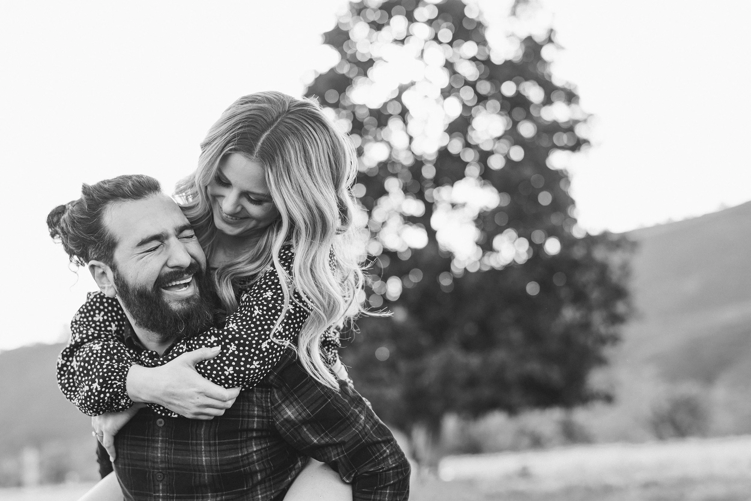 Orange County engagement photographer captures candid black and white moment of couple laughing together outdoors