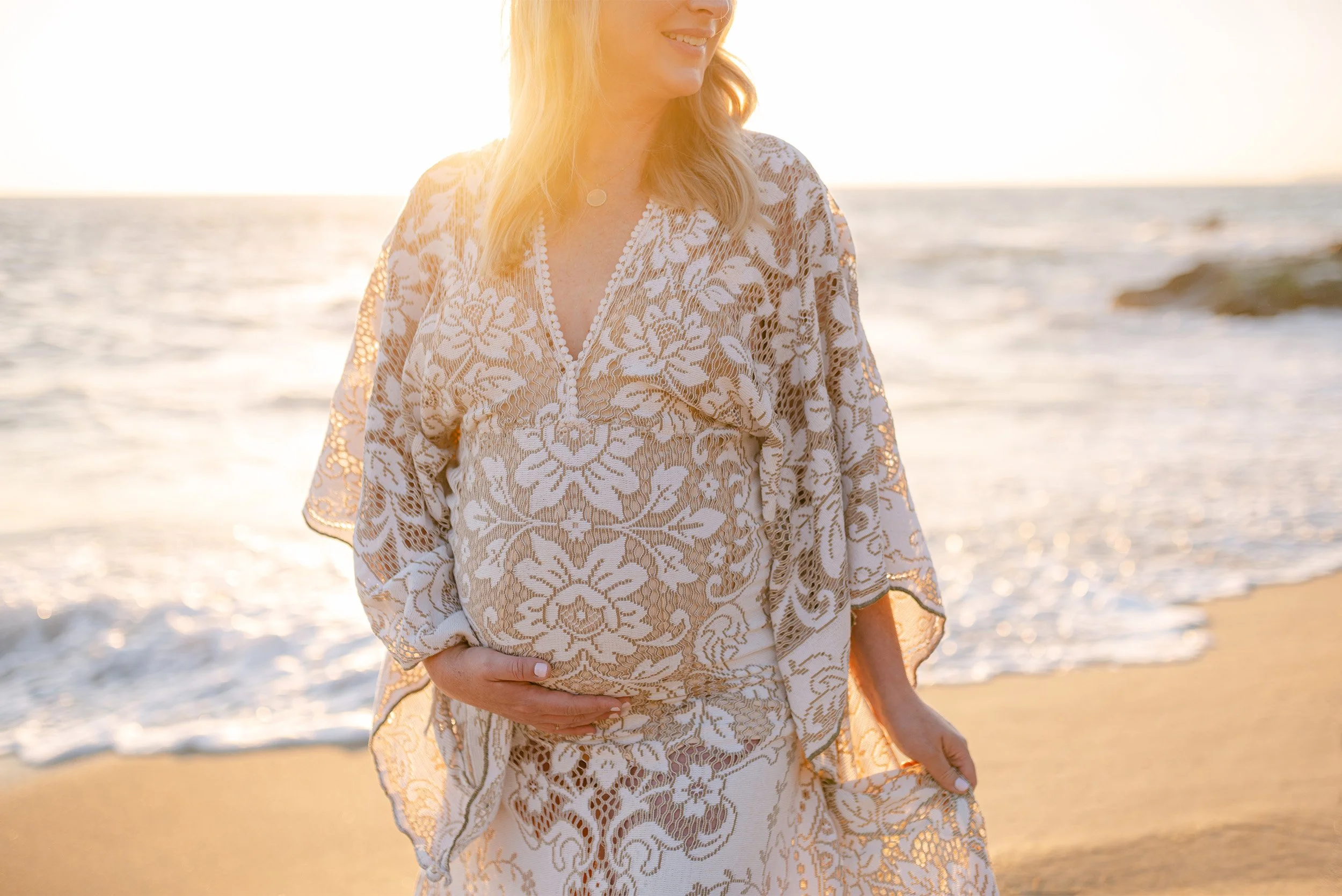 Close-up of pregnant belly in lace dress in Laguna Beach at golden hour, Laguna Beach maternity photographer