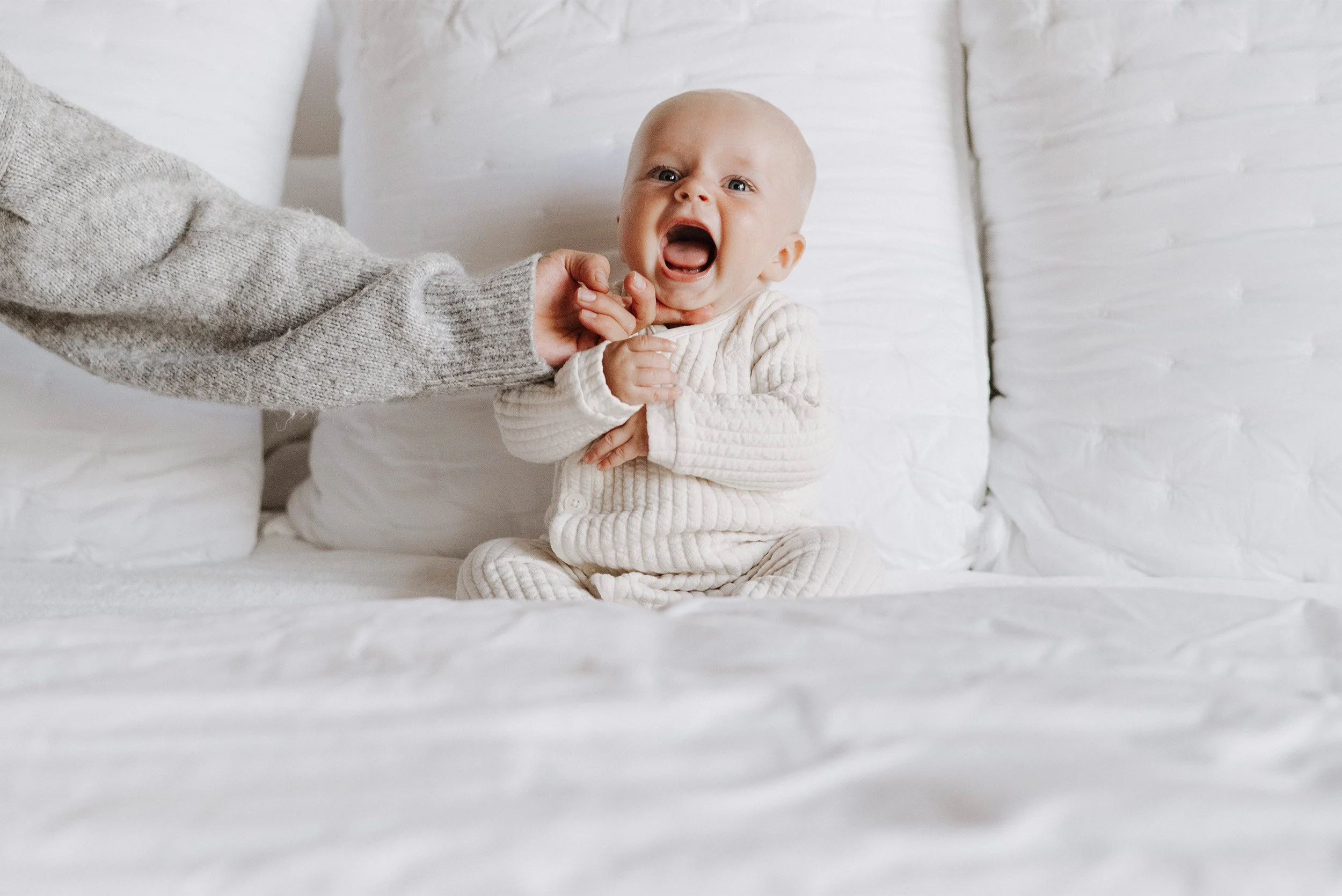 Family lifestyle photography featuring laughing baby in cream pajamas, Orange County family photographer