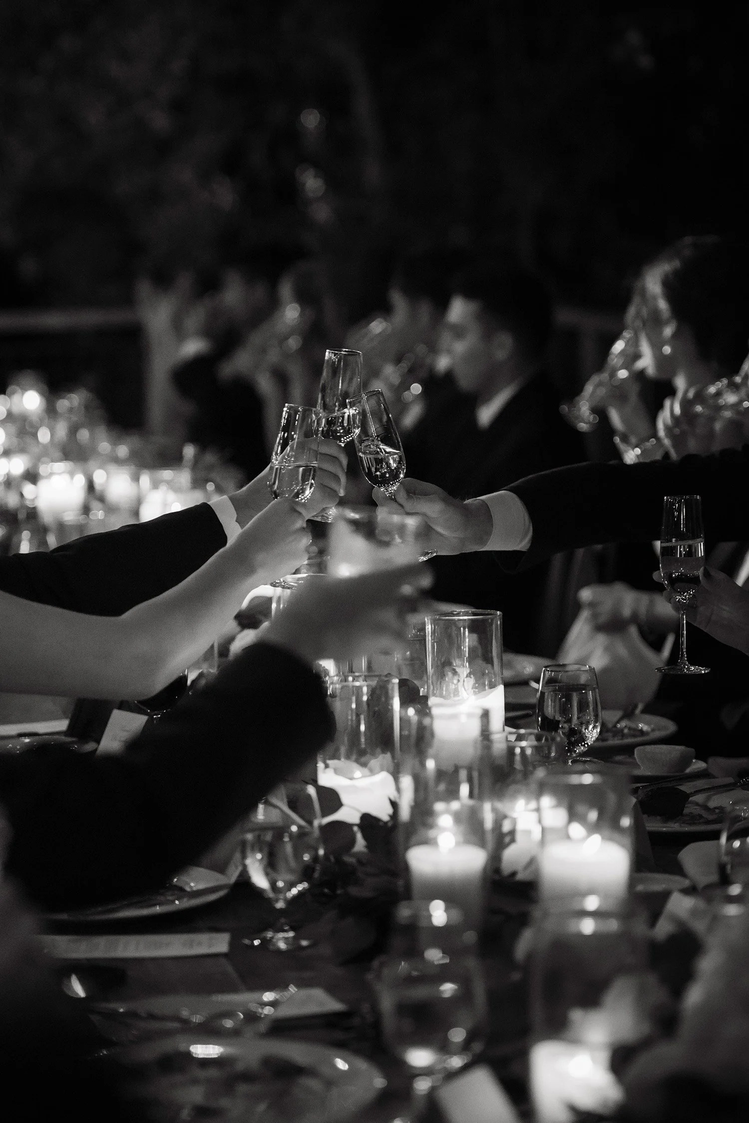 Award-winning wedding photographer in Montecito at San Ysidro Ranch captures candlelit champagne toast among reception guests, black and white