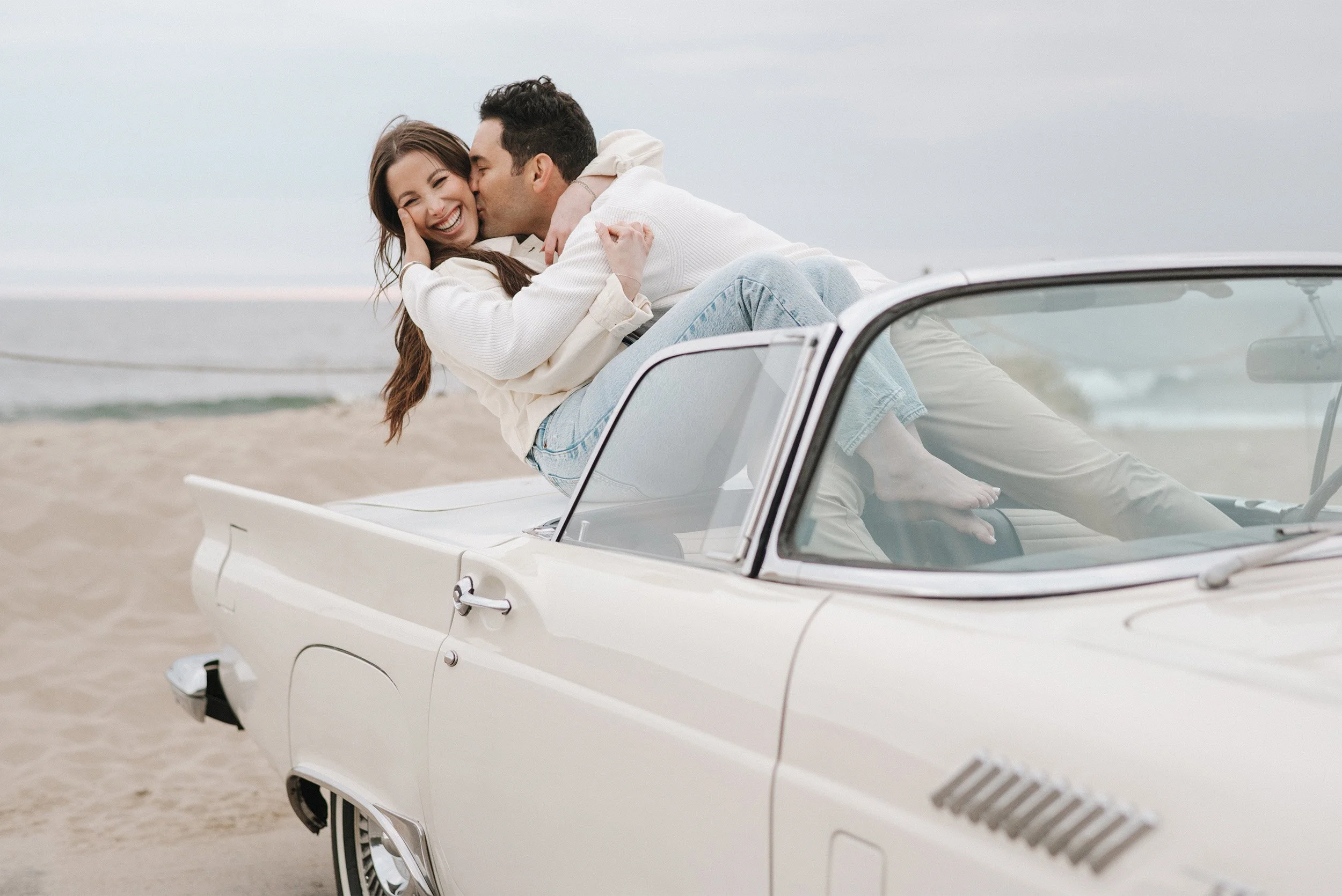 Highly recommended engagement photographer in Orange County captures couple laughing together in a vintage convertible on the Malibu beach